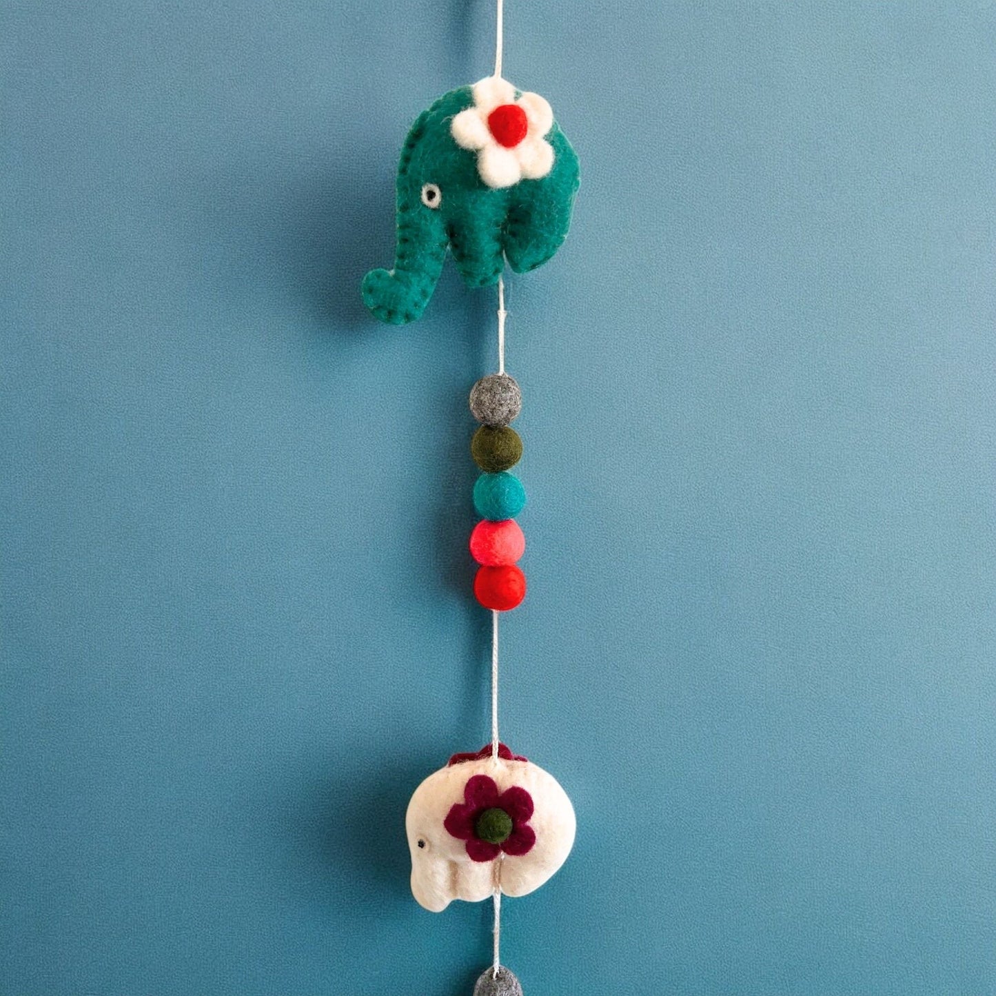 Handcrafted Felt Elephant Wall Hanging – 110 CM, Nepalese handmade felt elephant decor with colorful pom poms on blue wall