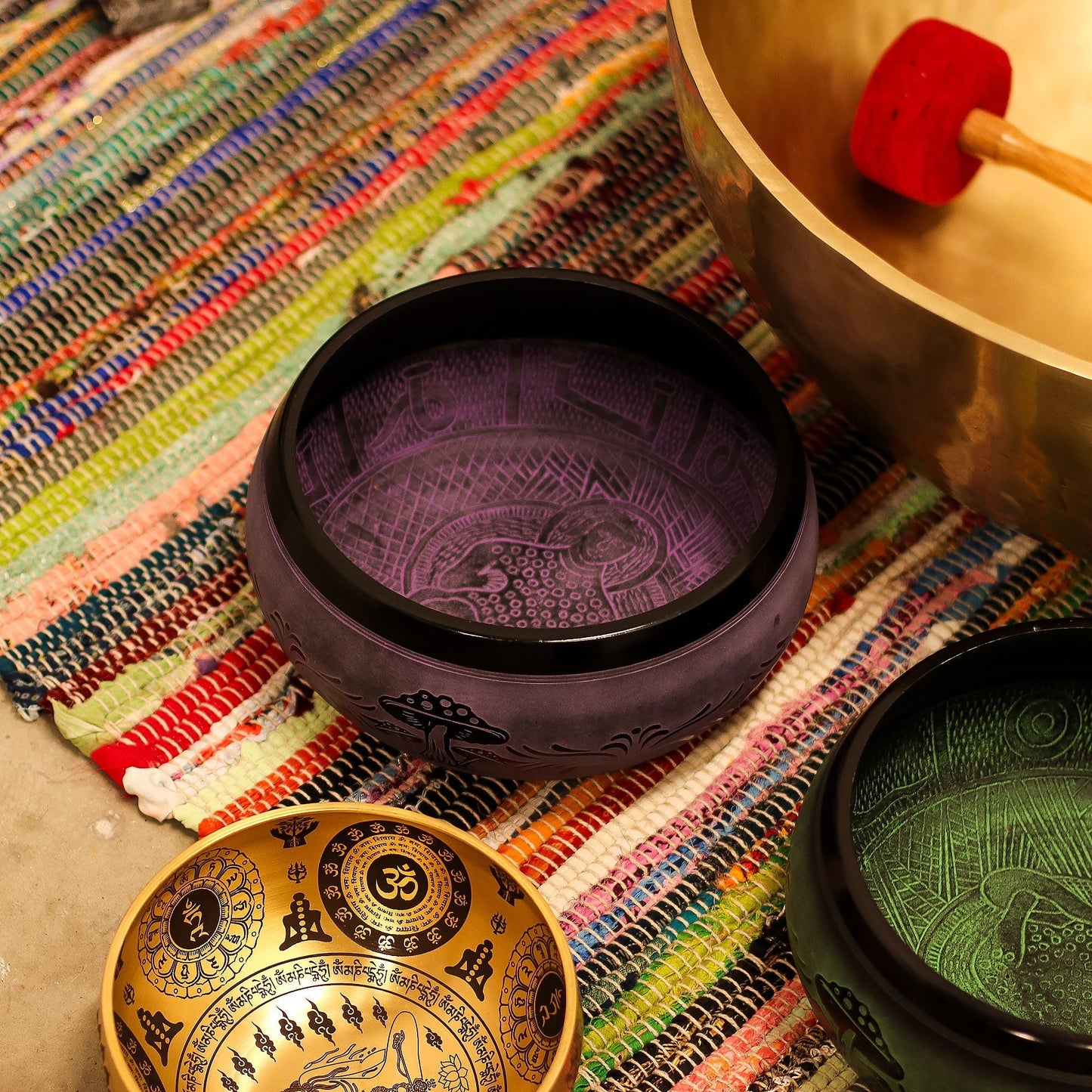 Brass Singing Bowl – Purple Haze 23x10.5 CM on colorful woven mat with mallet and other singing bowls