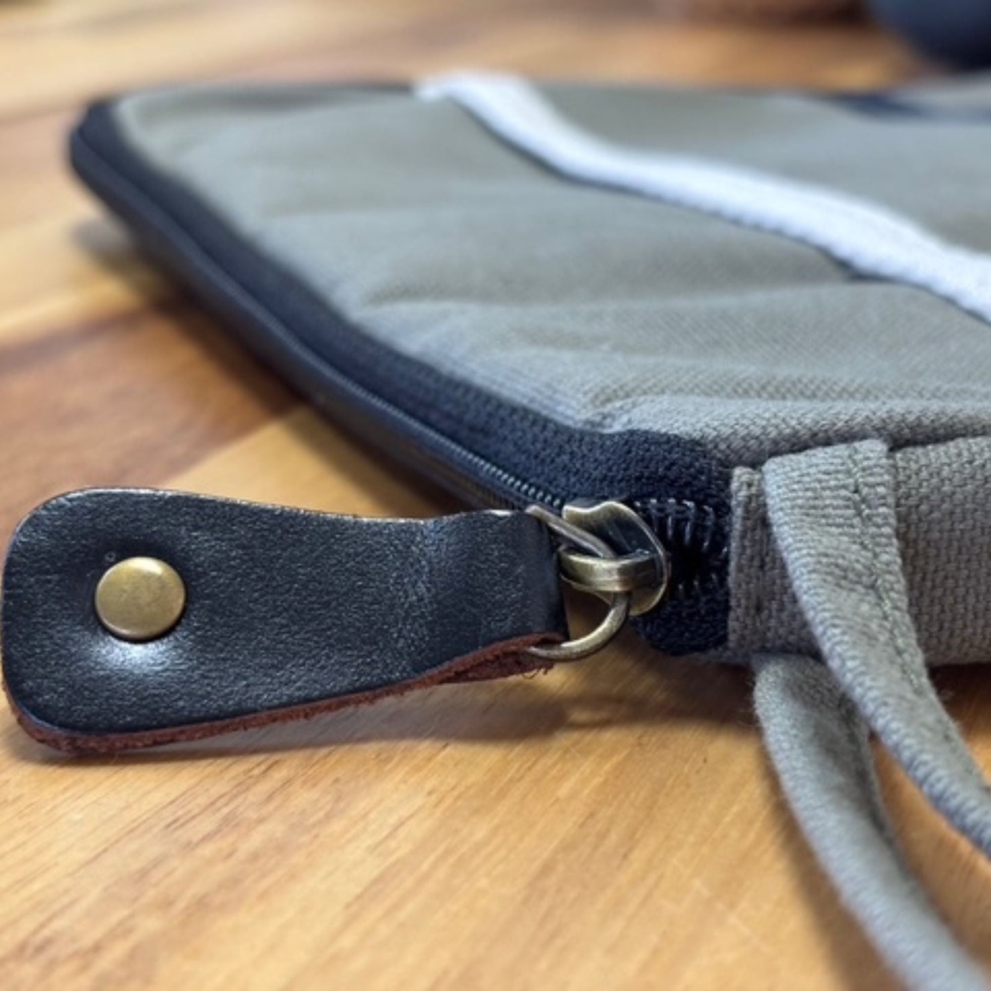 Olive surfplattfodral i jute & bomull – 21x29 CM närbild på dragkedja och läderflärp på olivfärgat tygfodral