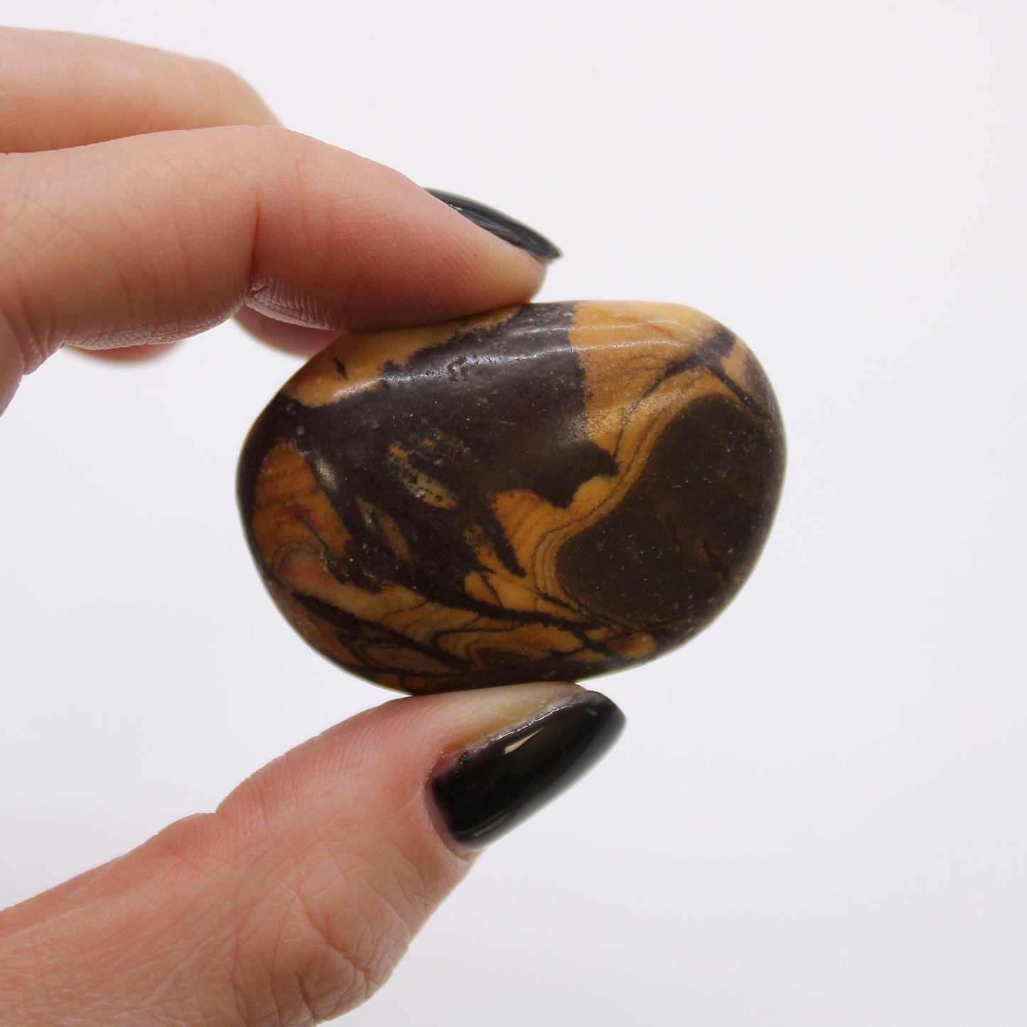 Alt Tag: Gemstone Tumble Stones – Picture Nguni Set polished stone held between fingers, brown and tan Nguni-like patterns