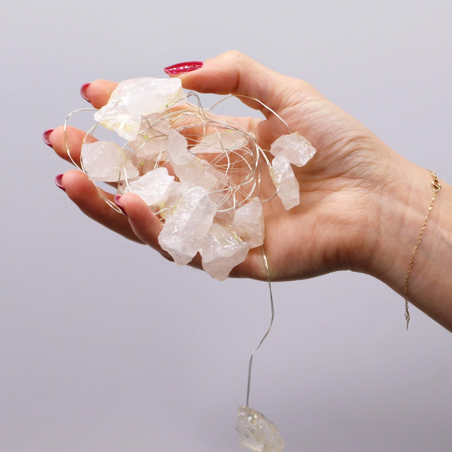 Alt Tag: Rock Quartz Gemstone Enchantment Lights – Decorative String held in hand with clear rock quartz chips and warm fairy wire lights