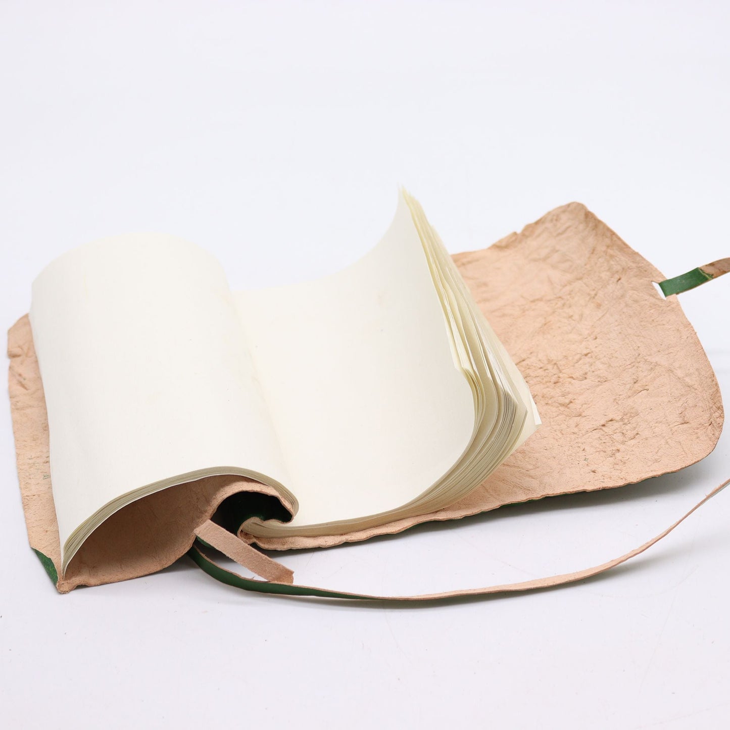Rullad resenotbok i läder – Grön (96 sidor, 21 × 15 CM) öppen vy som visar tomma sidor, rullat läderomslag med omslagsstängning och rem