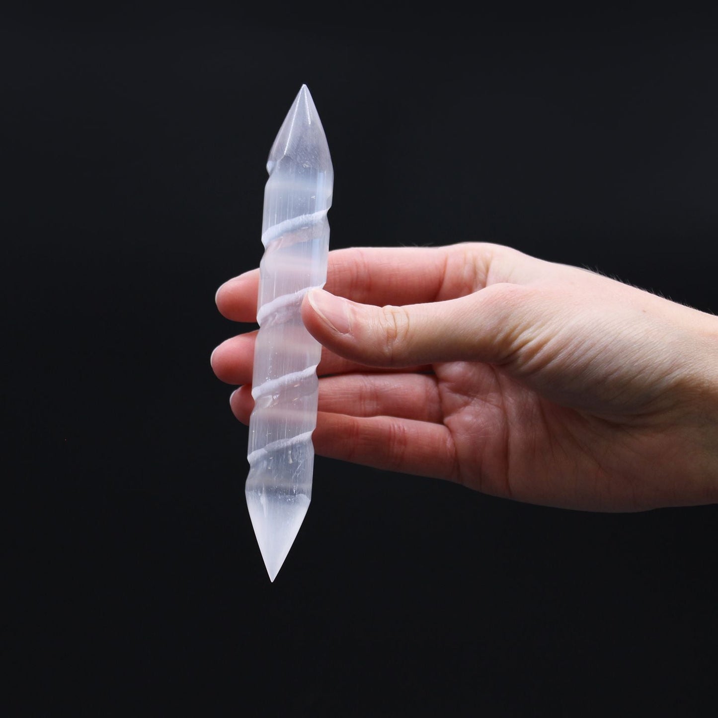 Alt Tag: Selenite Spiral Wand – 16 CM Double-Point, double-point spiral selenite crystal wand held in hand on black background