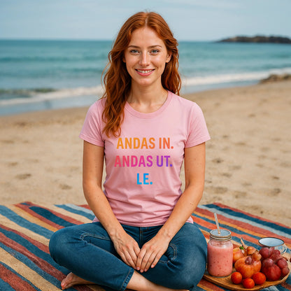 Andas Andas Ut Le Budskap 100% Organic Cotton T-Shirt pink graphic tee worn by woman sitting on beach blanket