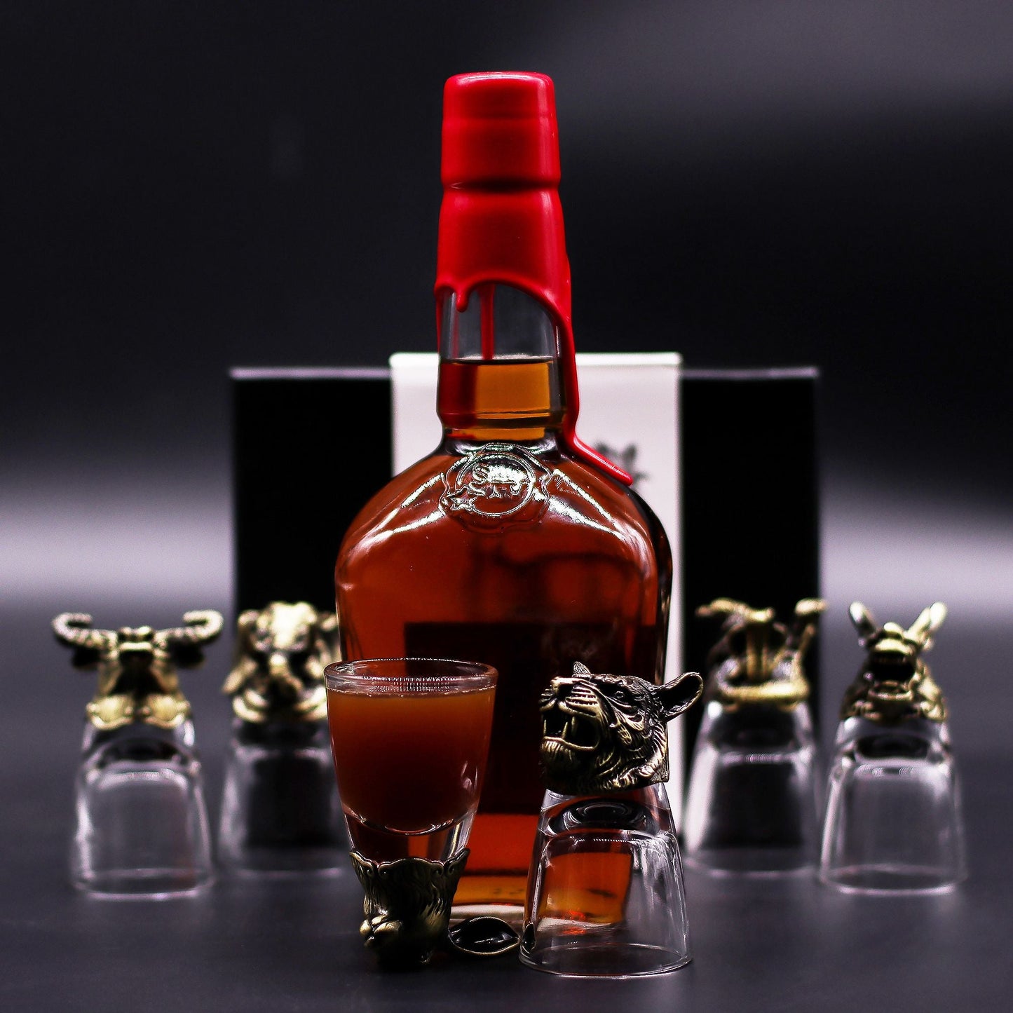 Antique Bronze Mystical Creatures Glasses – 50 ML set with bronze animal head shot glass beside liquor bottle on dark background