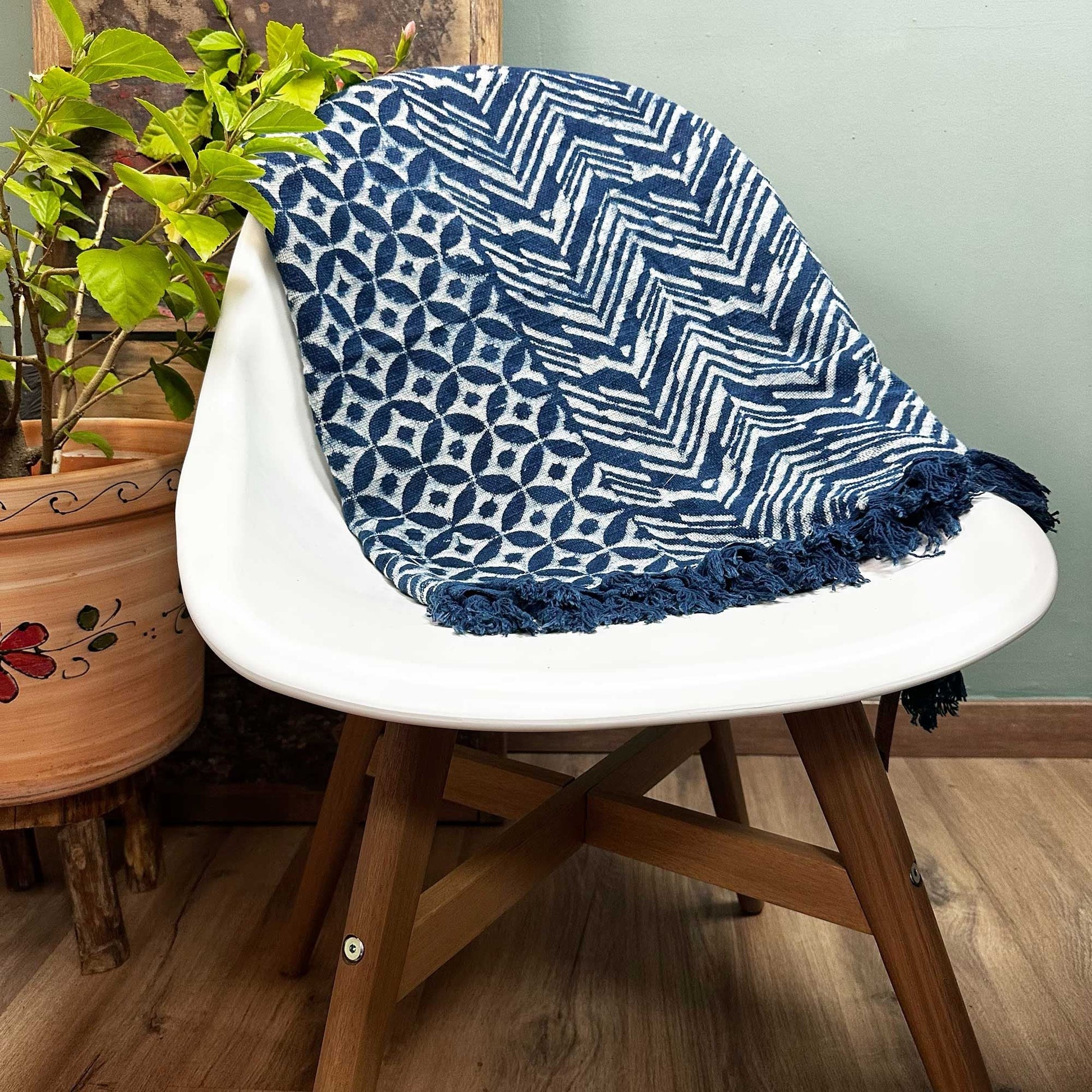 Handvävd indigopläd i bomull – 170x120 CM draperad över vit stol, indigofärgad bomullspläd med Namoona Waves-mönster och tofsar