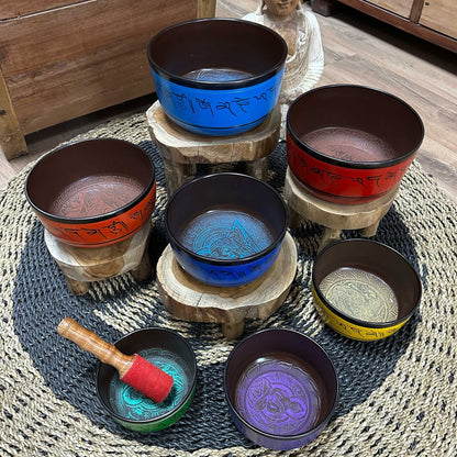 Handcrafted 7 chakra Tibetan singing bowl set (14–22cm) with colored symbols, arranged with included mallet