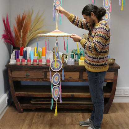Alt Tag: Hombre sosteniendo Bamboo & Cotton Rainbow Dreamcatcher – 140 CM de bambú y algodón con aros arcoíris pastel en interior