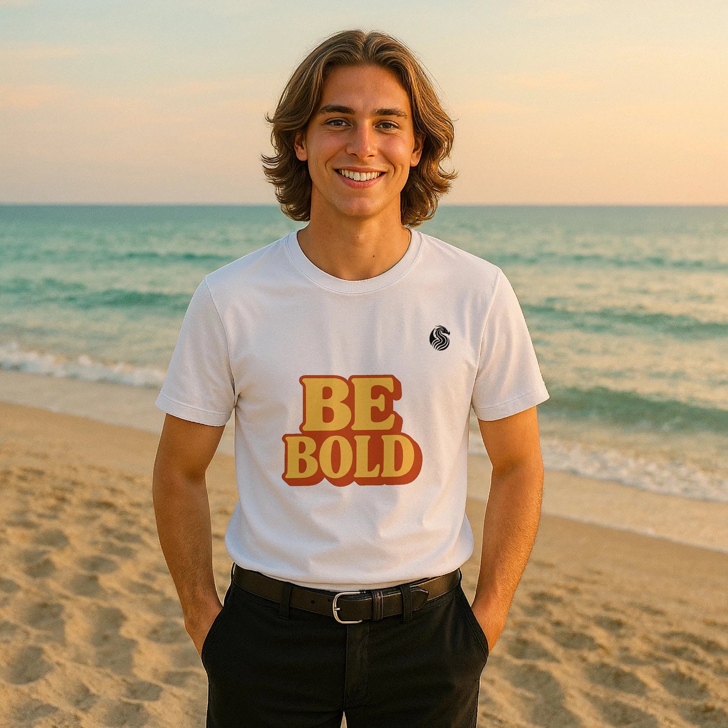 Alt Tag: Be Bold Youth 100% Organic Cotton T-Shirt on model, white tee with “BE BOLD” graphic, standing on beach at sunset