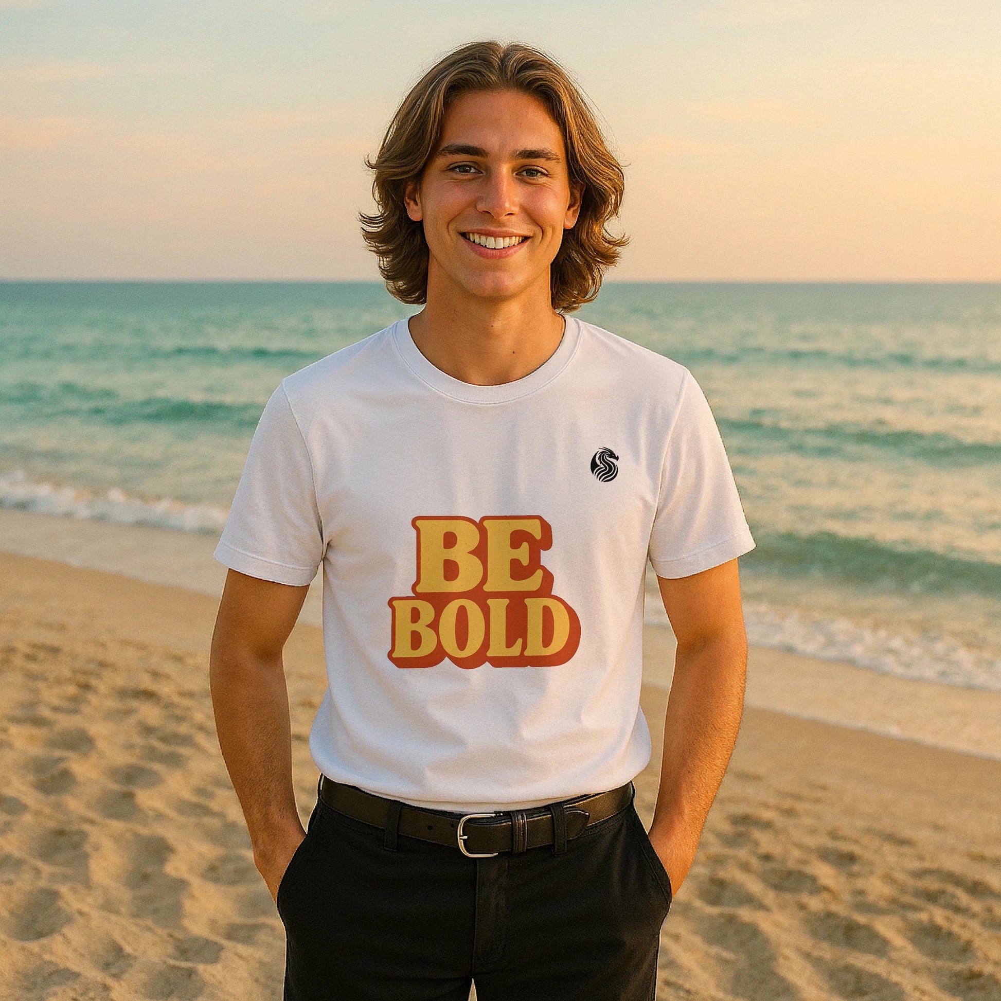 Alt Tag: Be Bold Youth 100% Organic Cotton T-Shirt on model, white tee with “BE BOLD” graphic, standing on beach at sunset