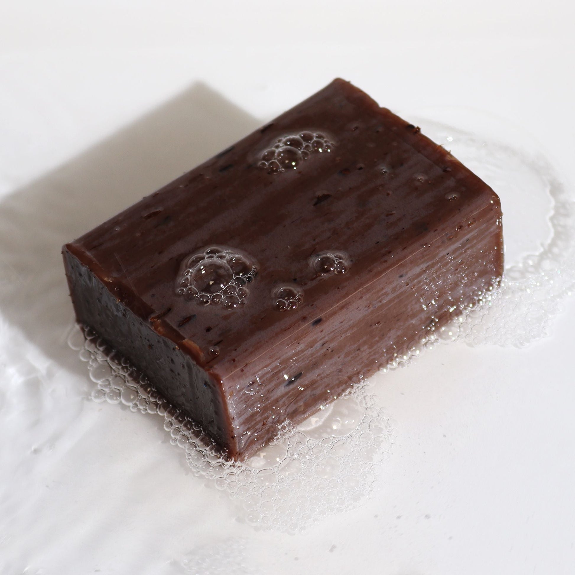 Alt Tag: Bentonite Clay Soap – Lavender & Vanilla 145G barra de jabón artesanal marrón con espuma sobre superficie blanca