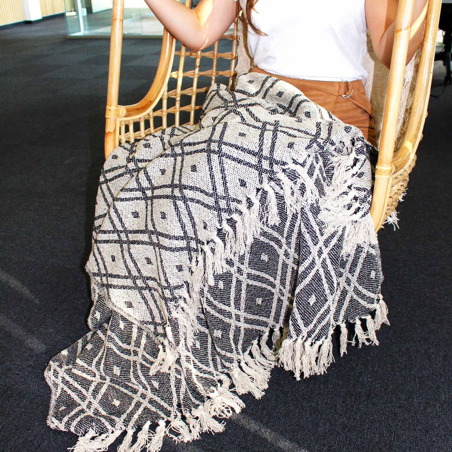 Alt Tag: Boho Comfort Throw – Black & Beige Regency manta tejida de algodón en blanco y negro con patrón geométrico y flecos sobre silla
