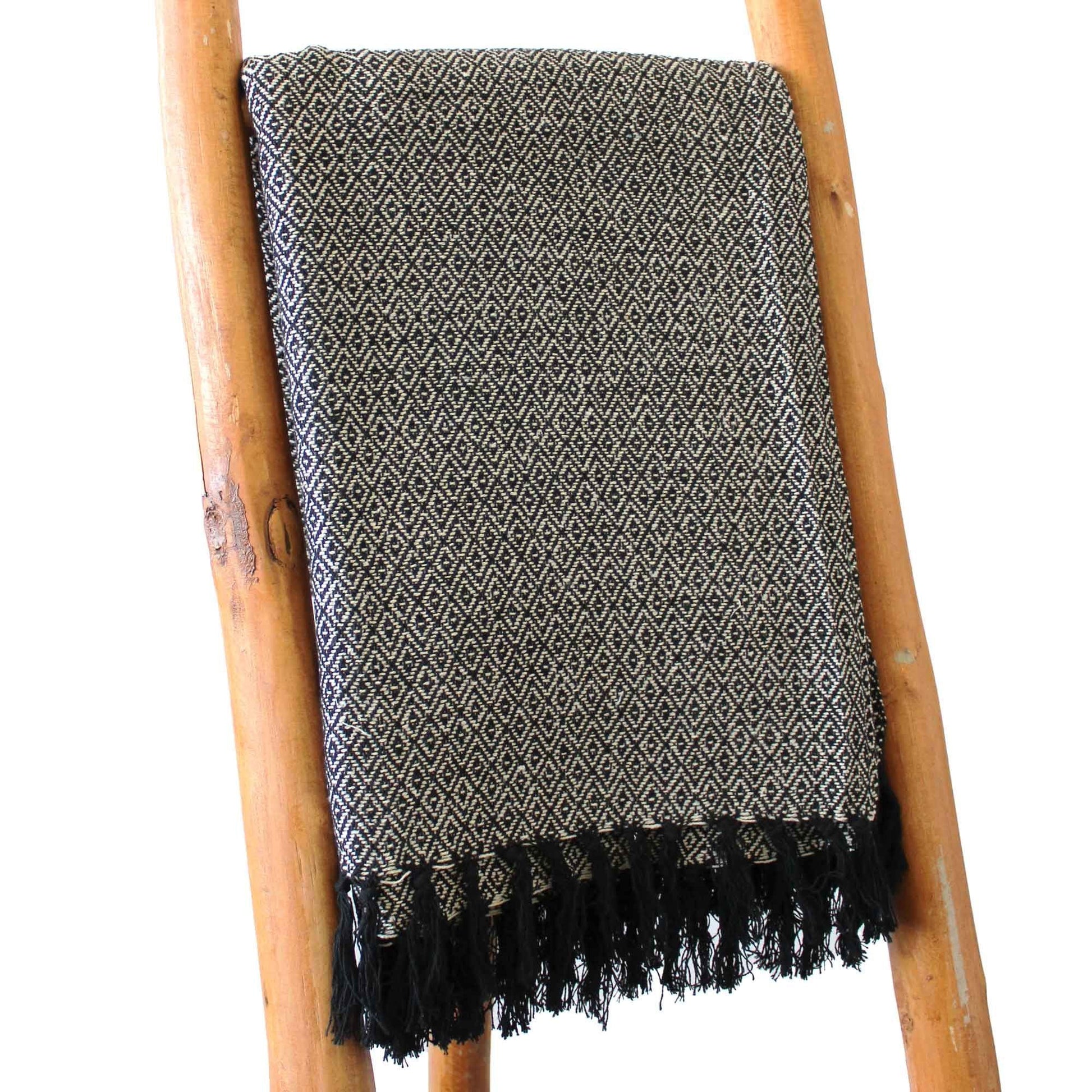 Alt Tag: Boho Comfort Throw – Kolgrått handvävt bomullspläd med bohotextur, fransade kanter, draperad på en trästege