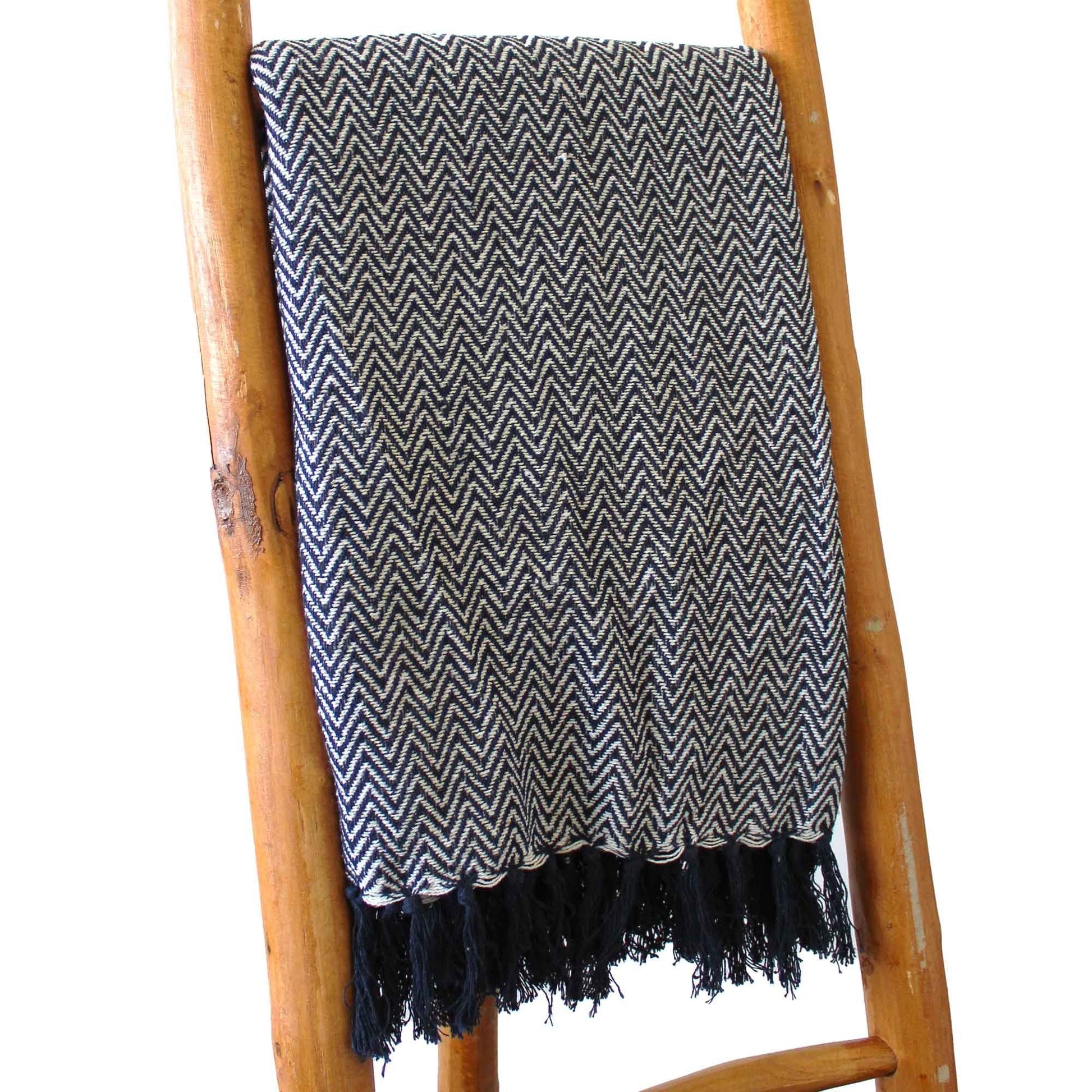 Boho Comfort-pläd – marinblå handvävd bomullspläd med marinblått sicksackmönster och fransar, draperad på en trästege