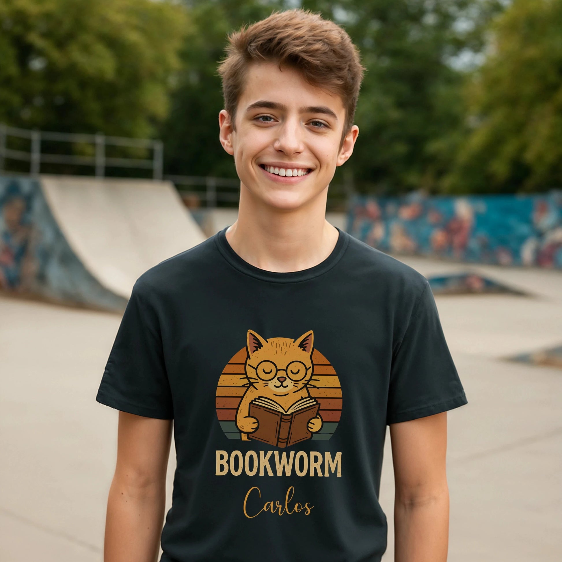 Bookworm Femenine Personalized Premium Unisex T-Shirt negra con gato lector y nombre Carlos, modelo sonriendo en skatepark