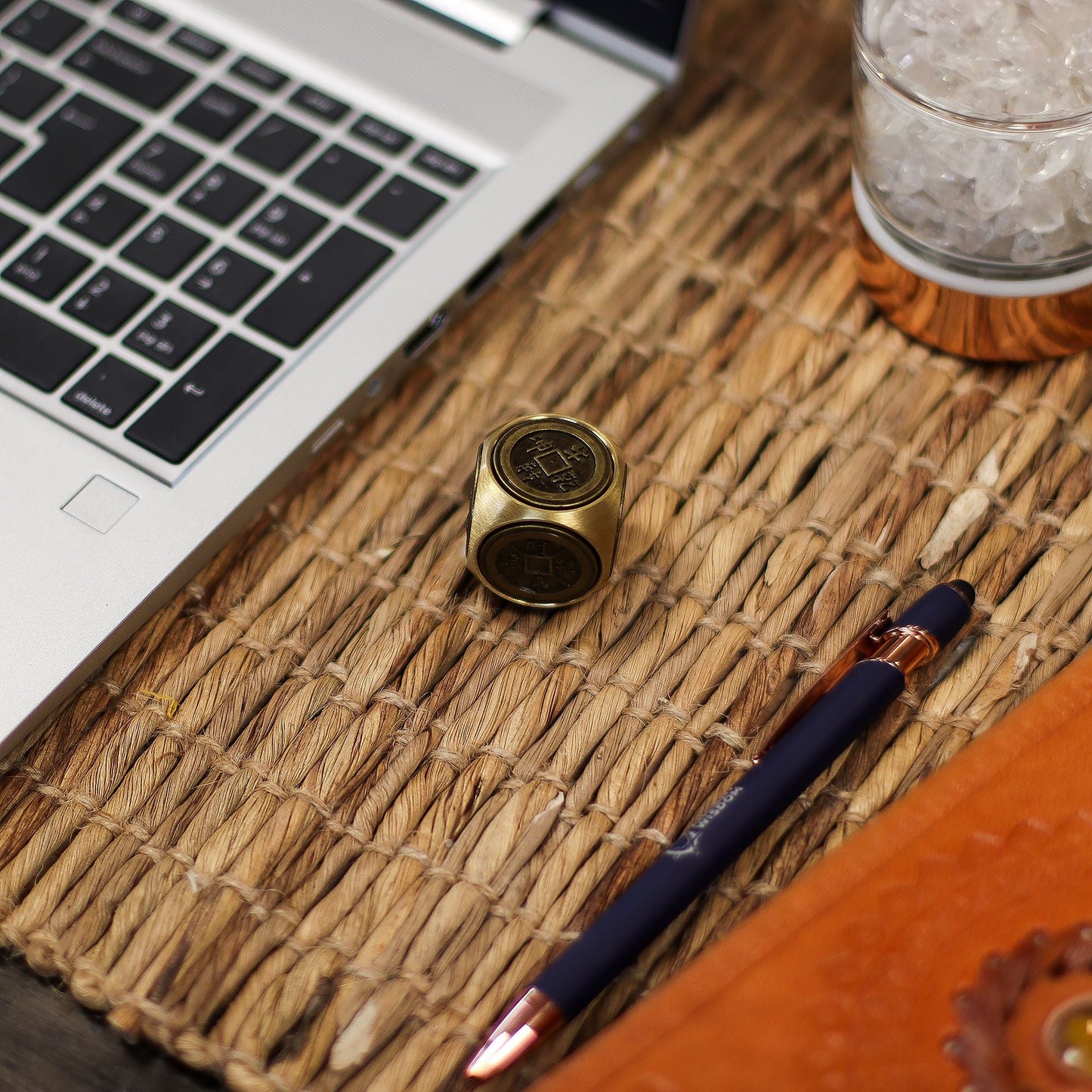 Brass Ancient Fortune Spinner – 3x3 CM Zodiac Emblems on desk mat beside laptop and pen, close-up of brass zodiac cube