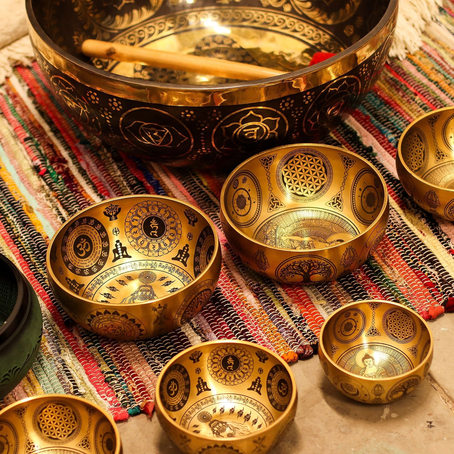 Mässingsetsade Buddha-sjungskålar – set med 4, 3,85 kg, handgjorda sjungskålar i mässing med heliga motiv på vävd matta med klubba