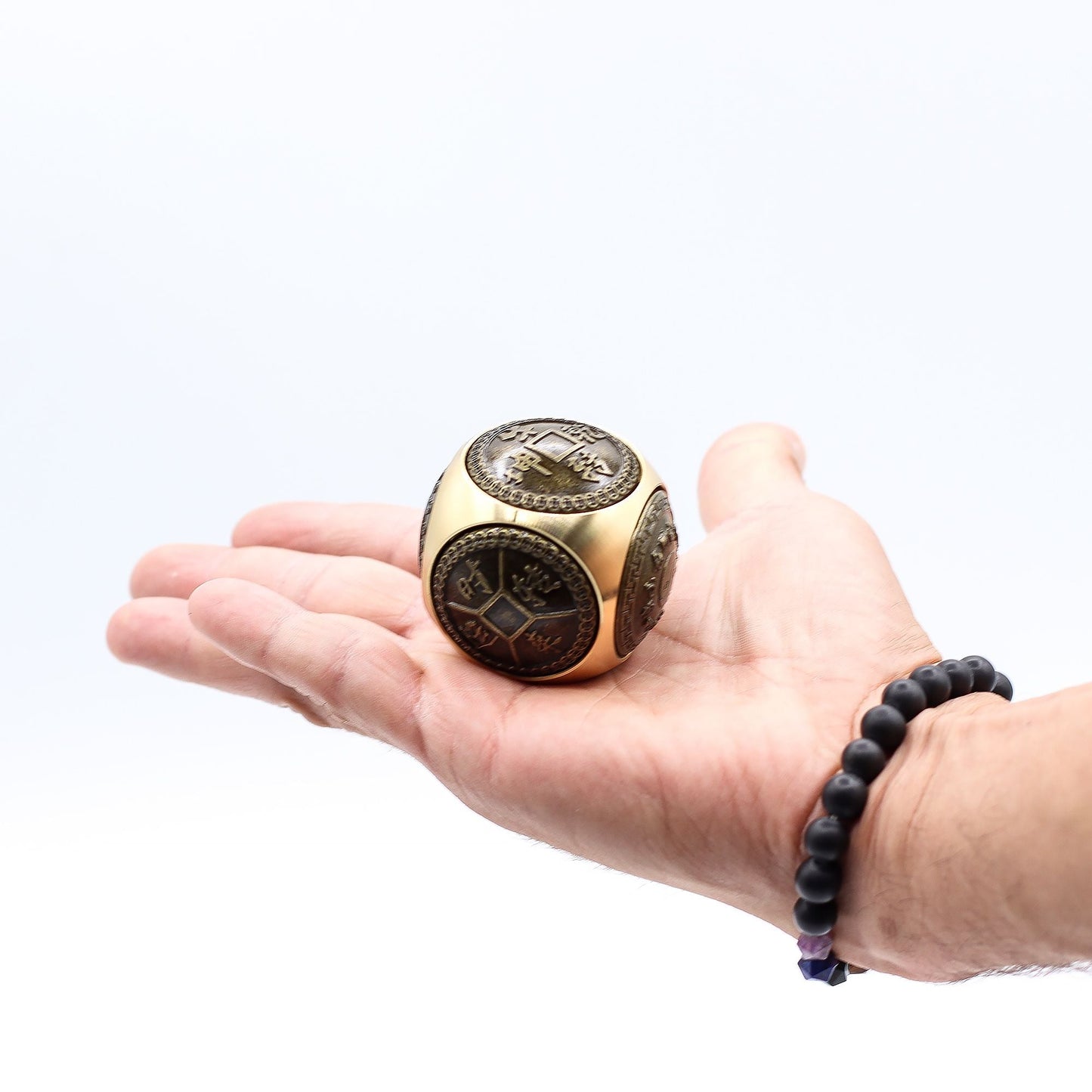 Alt Tag: Brass Feng Shui Wealth Spinner – 5.5 CM de latón con diseños chinos, mostrado en la palma de una mano sobre fondo blanco