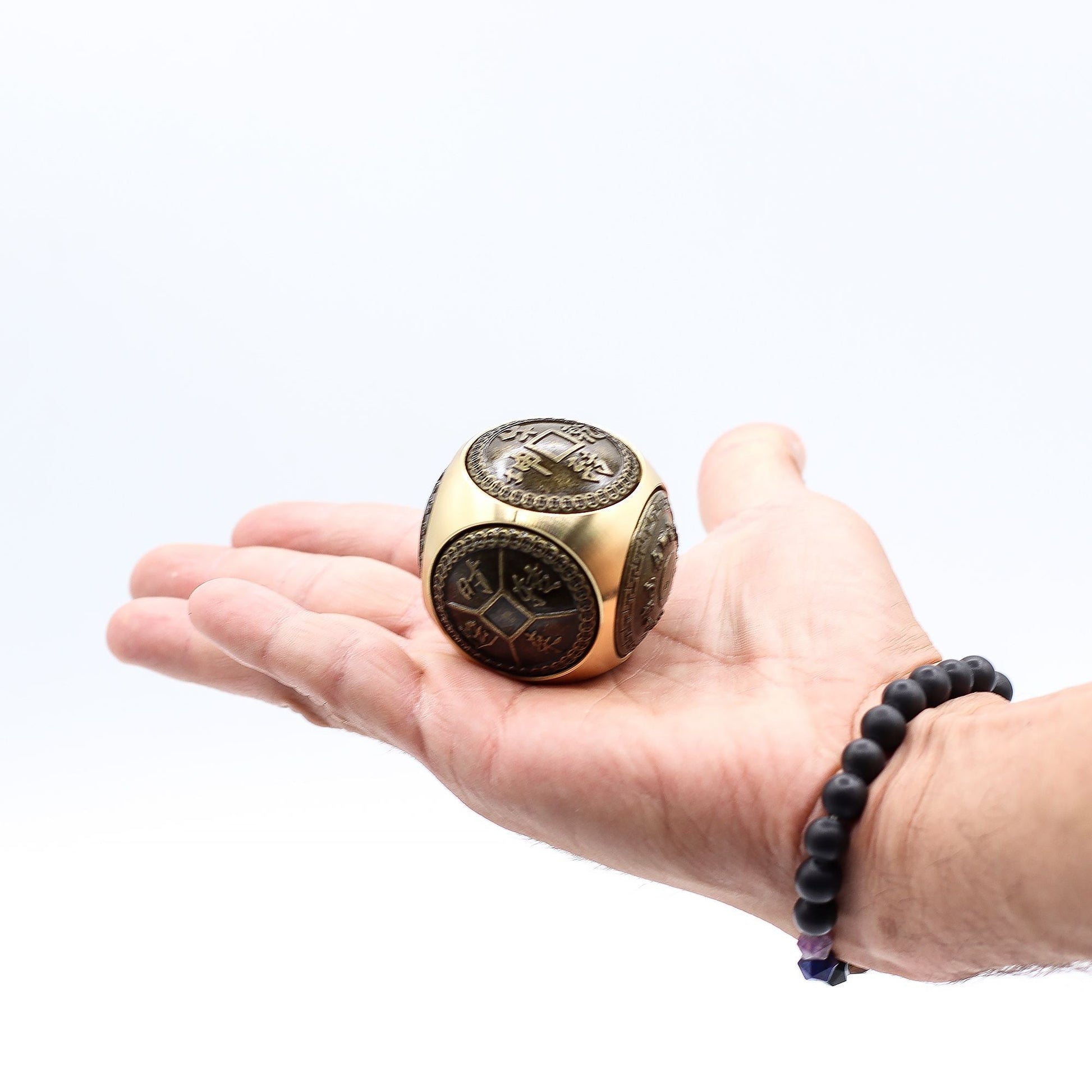Alt Tag: Brass Feng Shui Wealth Spinner – 5.5 CM de latón con diseños chinos, mostrado en la palma de una mano sobre fondo blanco