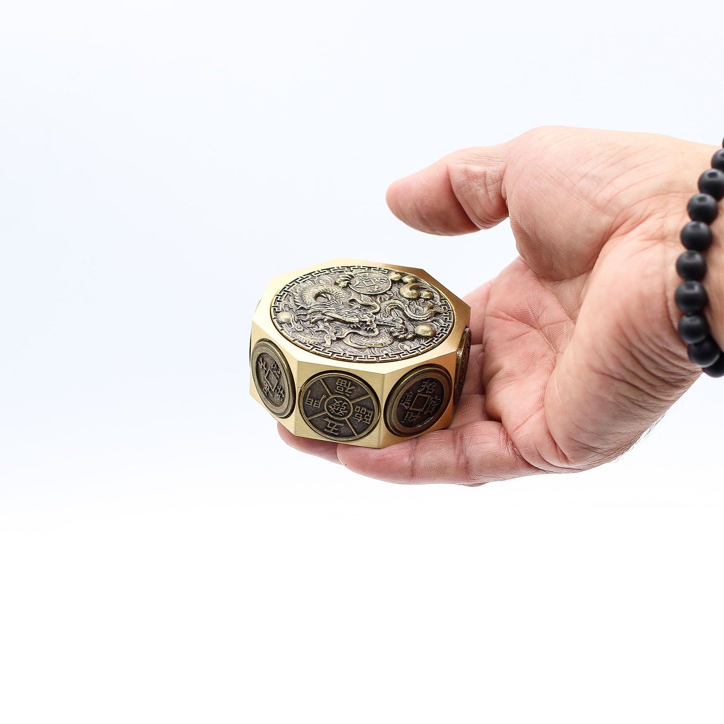 Brass Fortune Spinner – 6.5x3 CM en mano, spinner de latón con relieve de dragón y símbolos Feng Shui, vista de detalle
