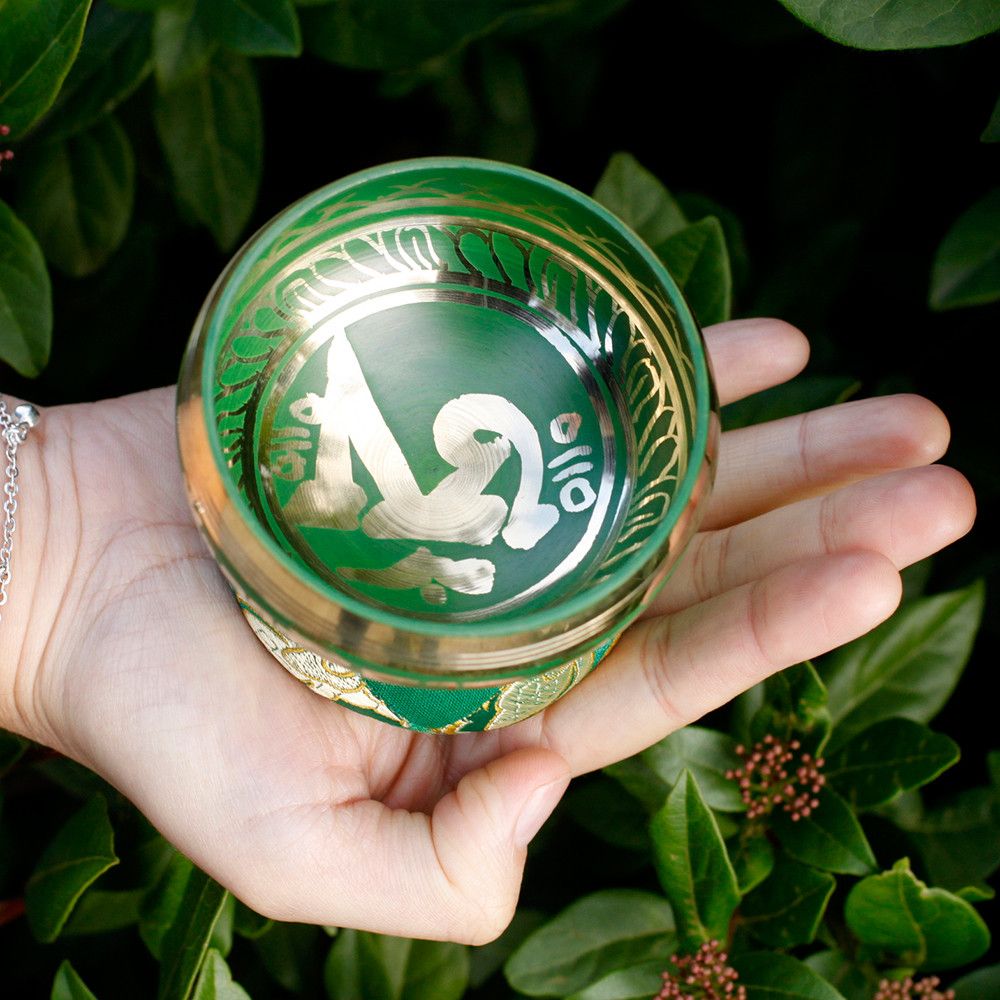 Alt Tag: Brass Tibetan Singing Bowl Set – 6x8 CM, cuenco tibetano de latón en mano con interior verde y grabado decorativo