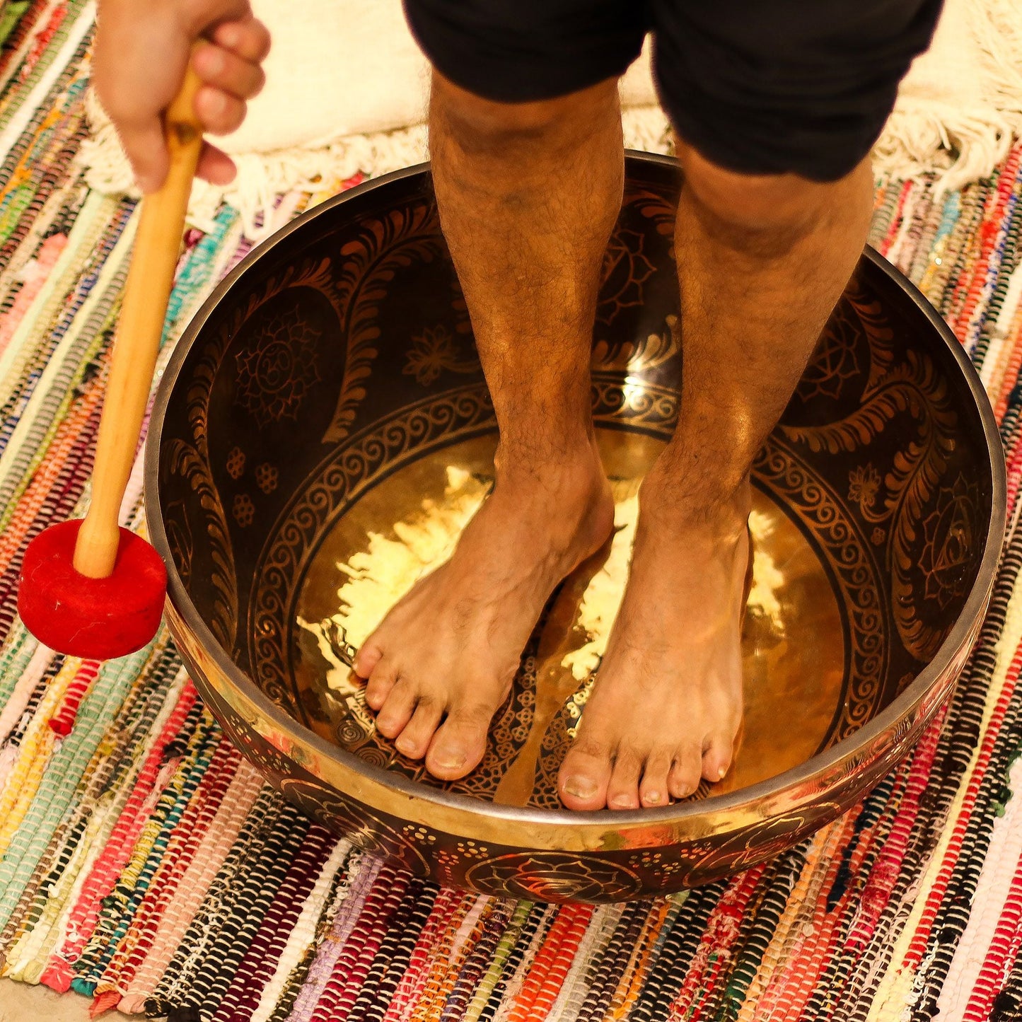 Brass Vibrational Standing Singing Bowl – 50x20CM with person standing inside on woven rug, holding red mallet