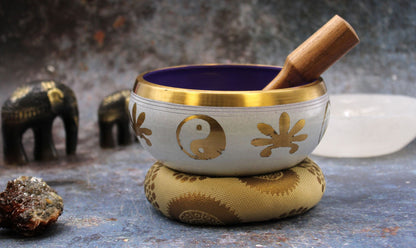 Alt Tag: Brass Yin-Yang Singing Bowl Set – White/Purple 14CM, brass and wood bowl with mallet on cushion, yin-yang design