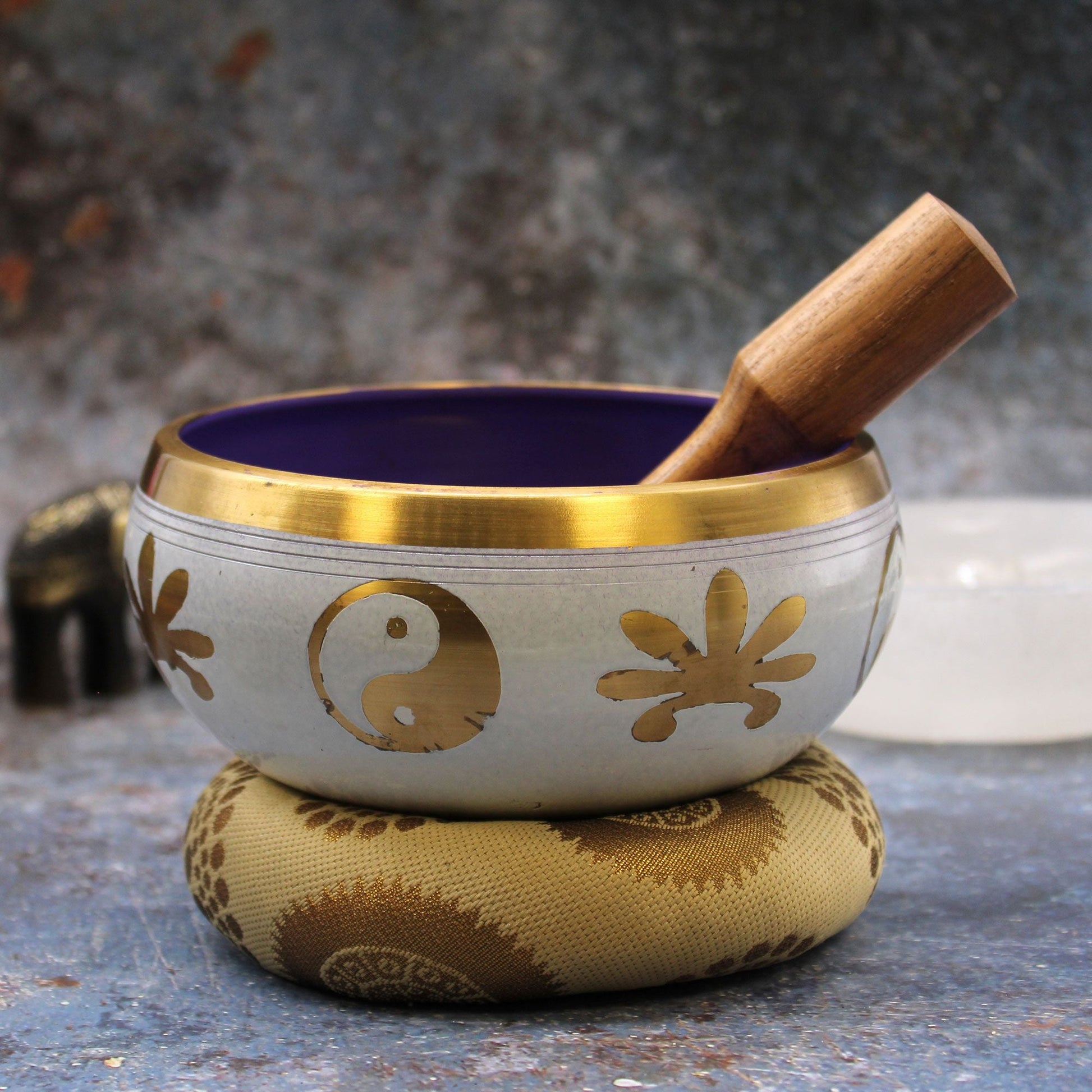 Alt Tag: Brass Yin-Yang Singing Bowl Set – White/Purple 14CM de latón, cuenco blanco y morado con mazo de madera sobre cojín