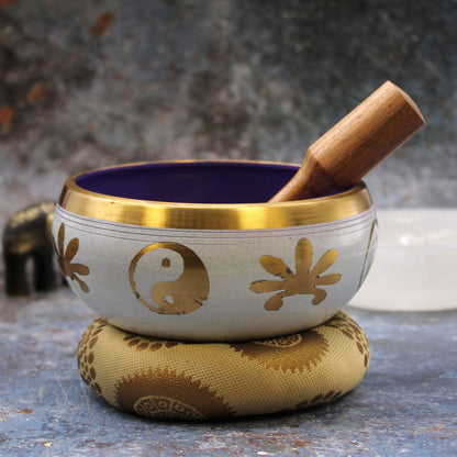 Alt Tag: Brass Yin-Yang Singing Bowl Set – White/Purple 14CM de latón, cuenco blanco y morado con mazo de madera sobre cojín