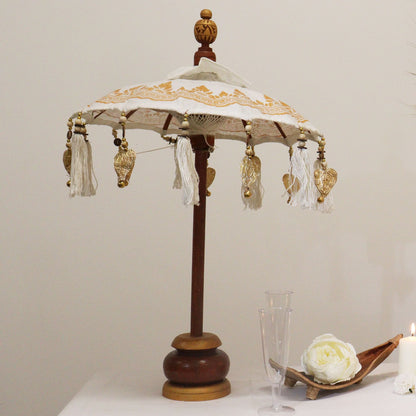 Alt Tag: Canvas Bali Decor Parasol – Vit & Guld 40CM dekorativ parasoll med vit canvas, guldkantade tofsar och Dorran-trästativ