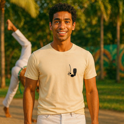 Alt Tag: Model wearing Capoeira Music Sustainable Unisex Tee beige with berimbau graphic, outdoor capoeira training in background