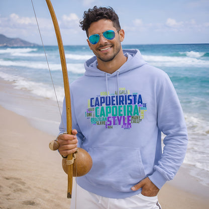 Capoeira Sustainable Unisex Hoodie in light blue organic cotton with capoeira word art print, worn on beach with berimbau
