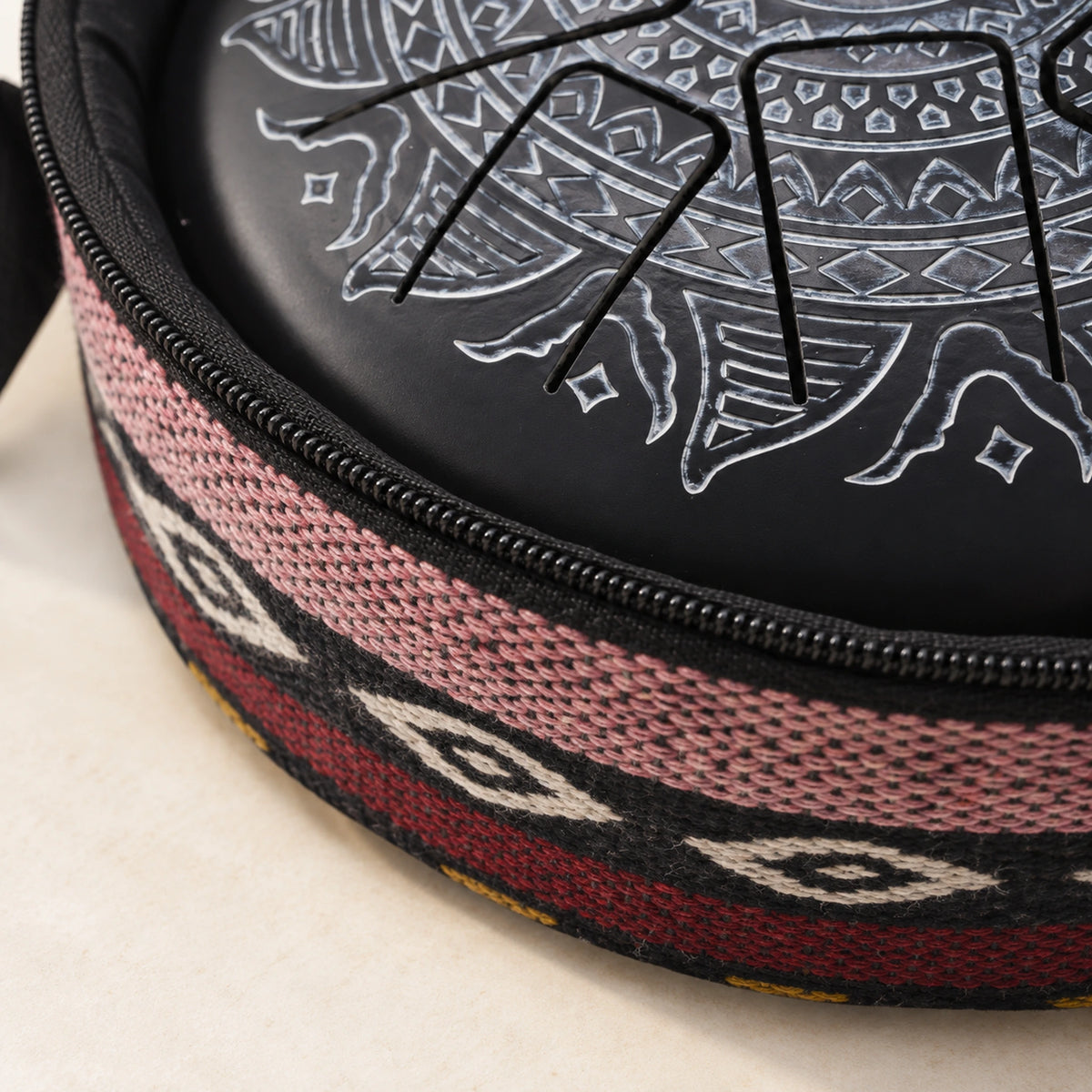 Detail of the open carrying bag's patterned textile edge and black zipper, with part of the drum visible inside.
