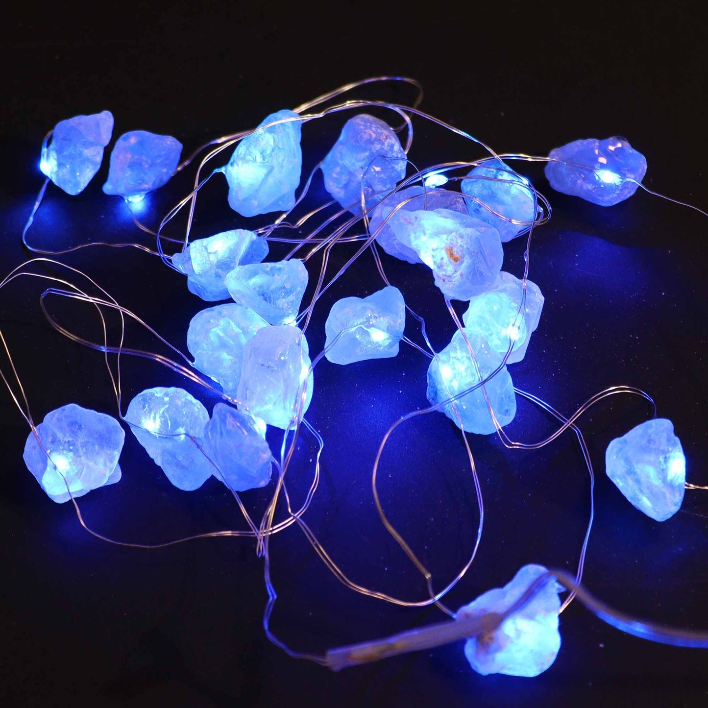 Celestit Ädelstensmagi Lights – Dekorativ ljusslinga med glödande blå celestitstenar på koppartråd, närbild mot mörk bakgrund