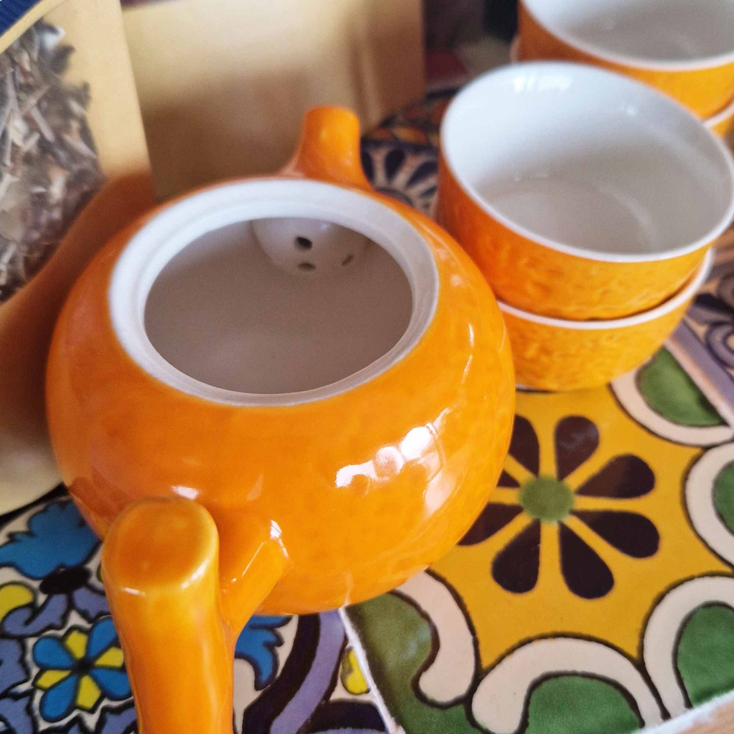 Alt Tag: Ceramic Herbal Teapot Set – 200ML & 50ML Cups, tetera cerámica naranja con 4 tazas pequeñas sobre mantel estampado