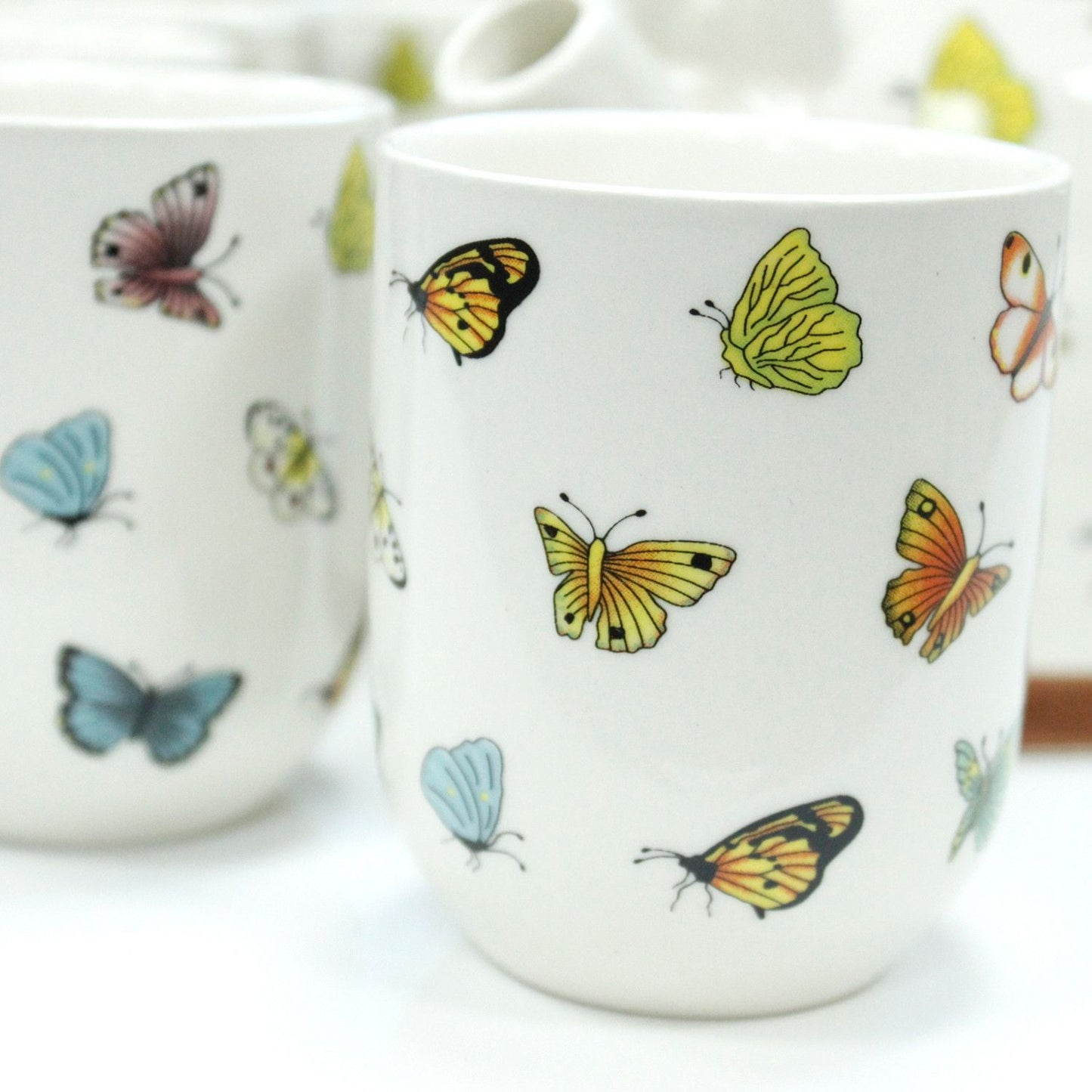 Alt Tag: Ceramic Herbal Teapot Set – Butterflies – 6 Cups ceramic teacup with colorful butterfly pattern, close-up of matching cups