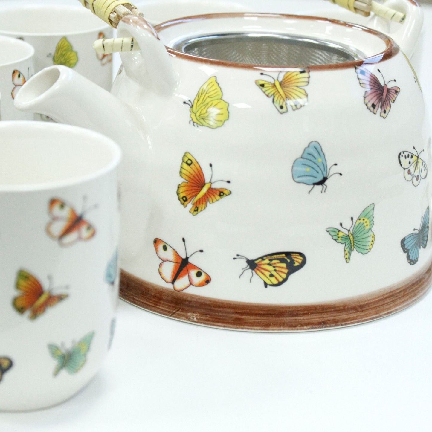 Alt Tag: Ceramic Herbal Teapot Set – Butterflies – 6 Cups, ceramic teapot with butterfly design and matching cup close-up