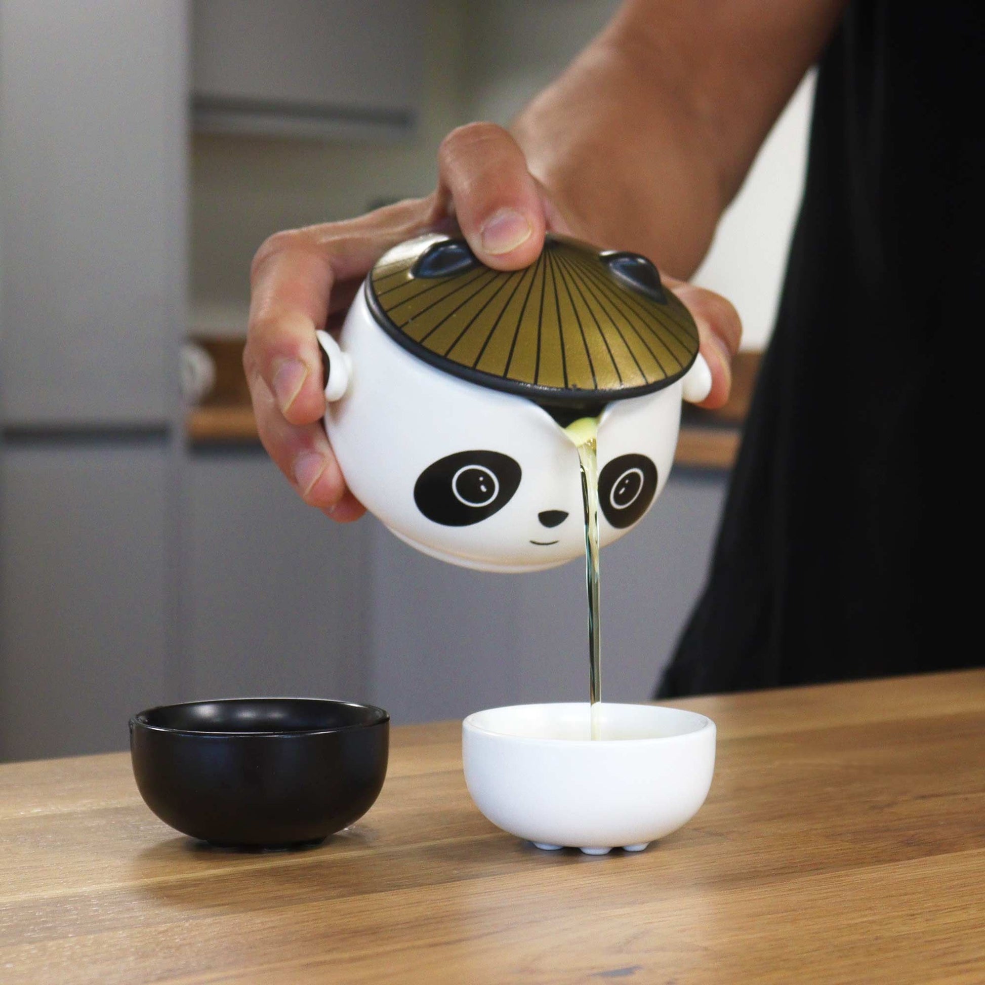 Alt Tag: Ceramic Herbal Teapot Set – 2 Cups & Travel Case panda ceramic teapot pouring tea into cup, includes two cups and travel case
