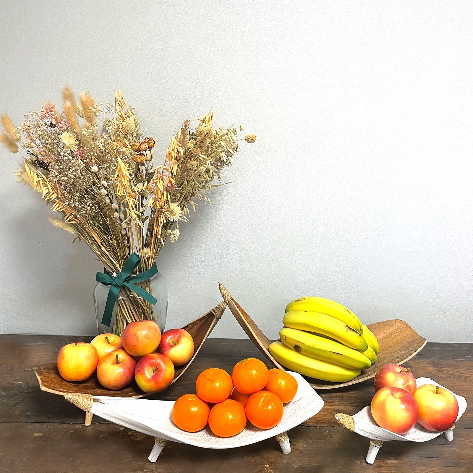 Fruktskålset i kokosblad – vitkalkad med bananer, äpplen och apelsiner på ett bord, handgjorda skålar i kokosblad med vitkalkad finish