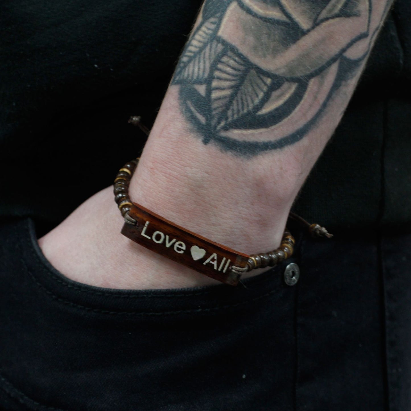 Alt Tag: Coconut Wood Bangle – LoveAll Slogan bracelet on wrist, natural coconut wood bar engraved “Love All” with beaded band, 7.5x3x0.5 cm