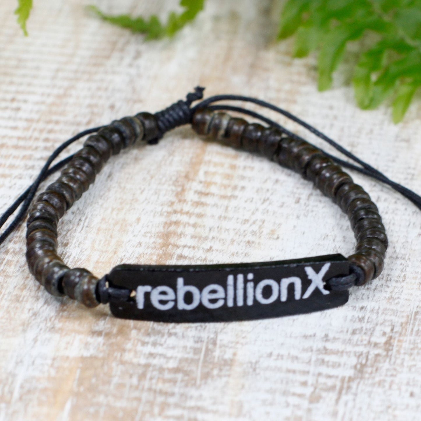Alt-tagg: Armband med slogan i kokosträ – Rebellion X justerbart armband med pärlor i kokosträ med svart sloganplatta RebellionX