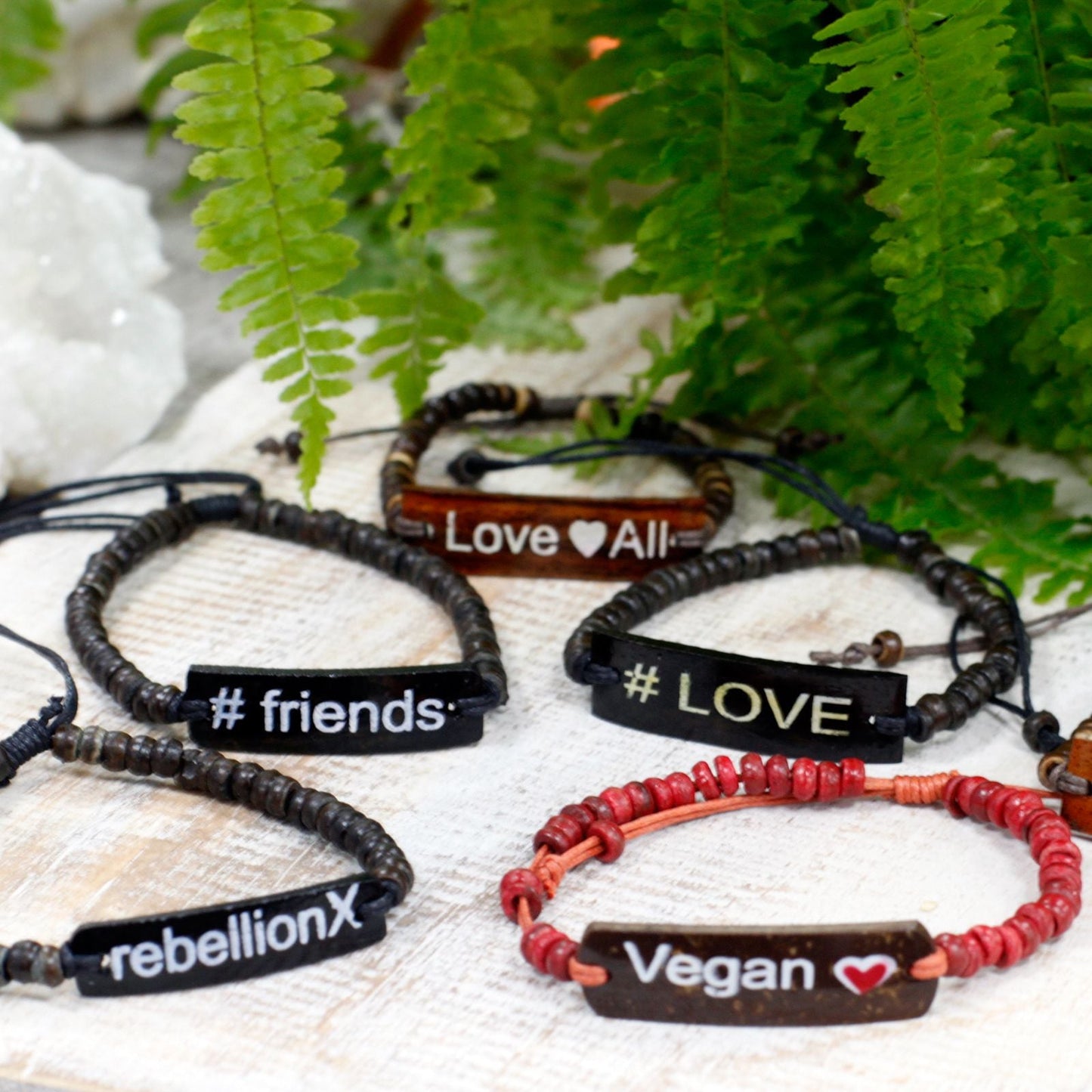 Kokosträ Sloganarmband – Rebellion X set med slogan-armringar i kokosträ med graverade tags #LOVE #friends Vegan Love All on table