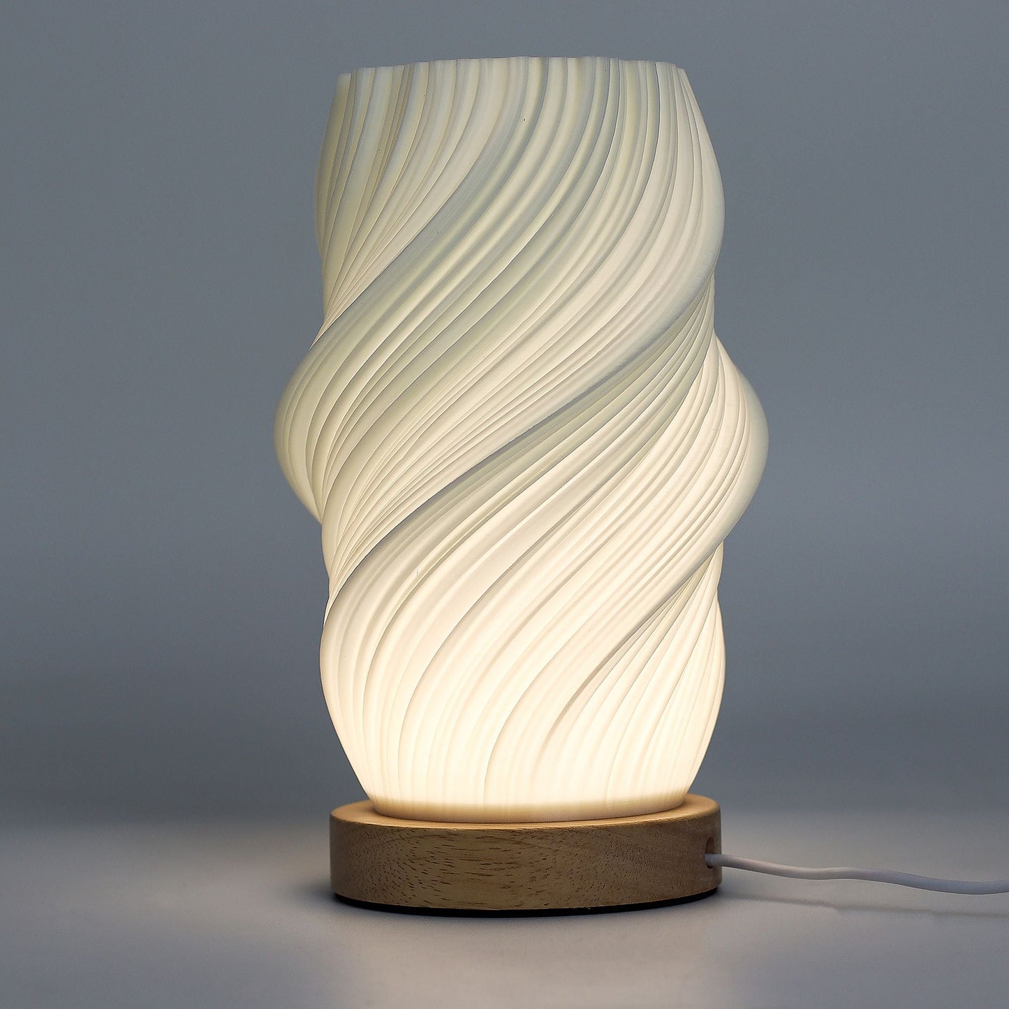 Alt Tag: Cornstarch PLA New Wave Lamp – Cloud Twisted, lámpara de mesa moderna con pantalla blanca en espiral y base de madera, encendida