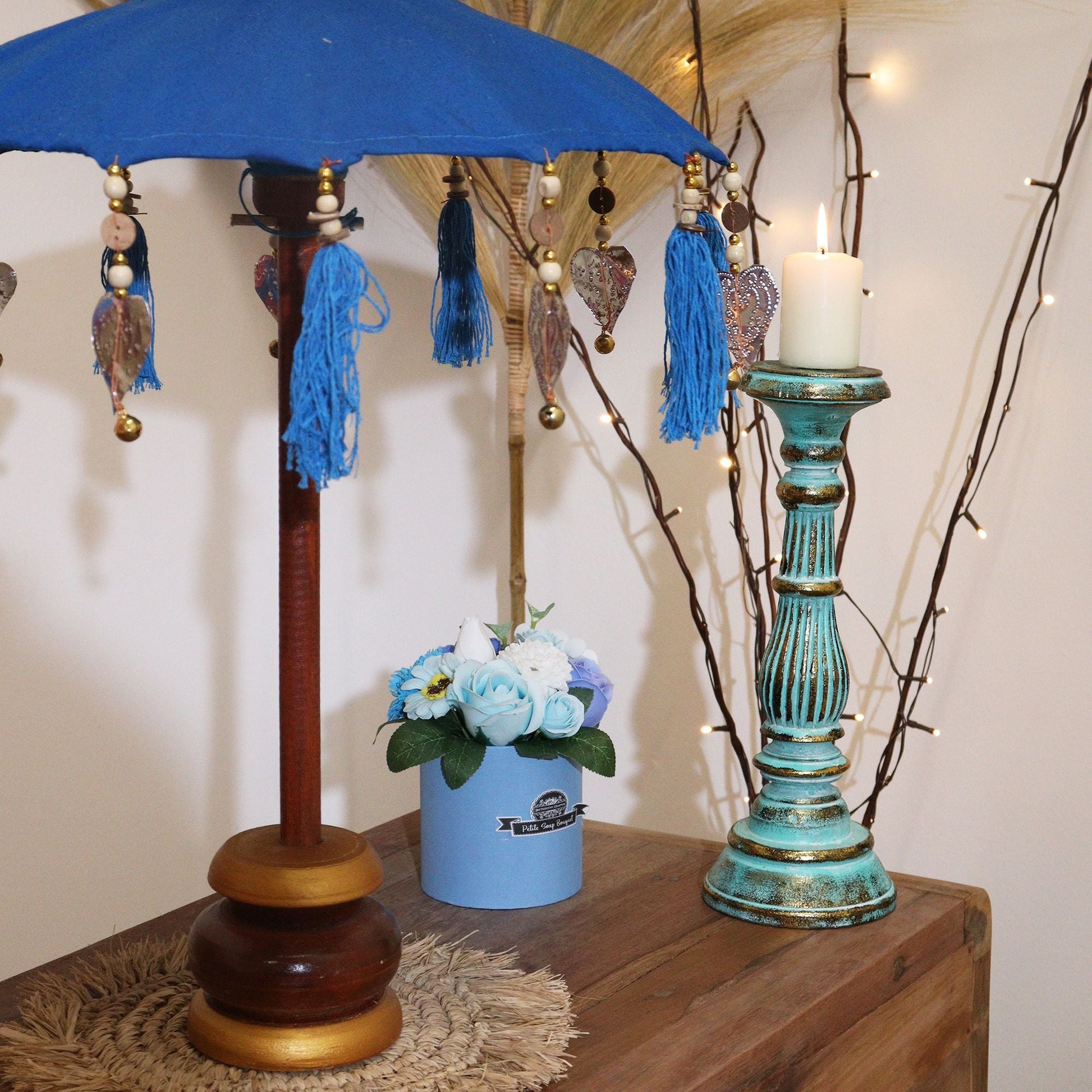 Alt Tag: Cotton Bali Decor Parasol – Turquoise 40CM decor parasol de algodón azul turquesa con borlas, sobre mesa de madera en ambiente interior