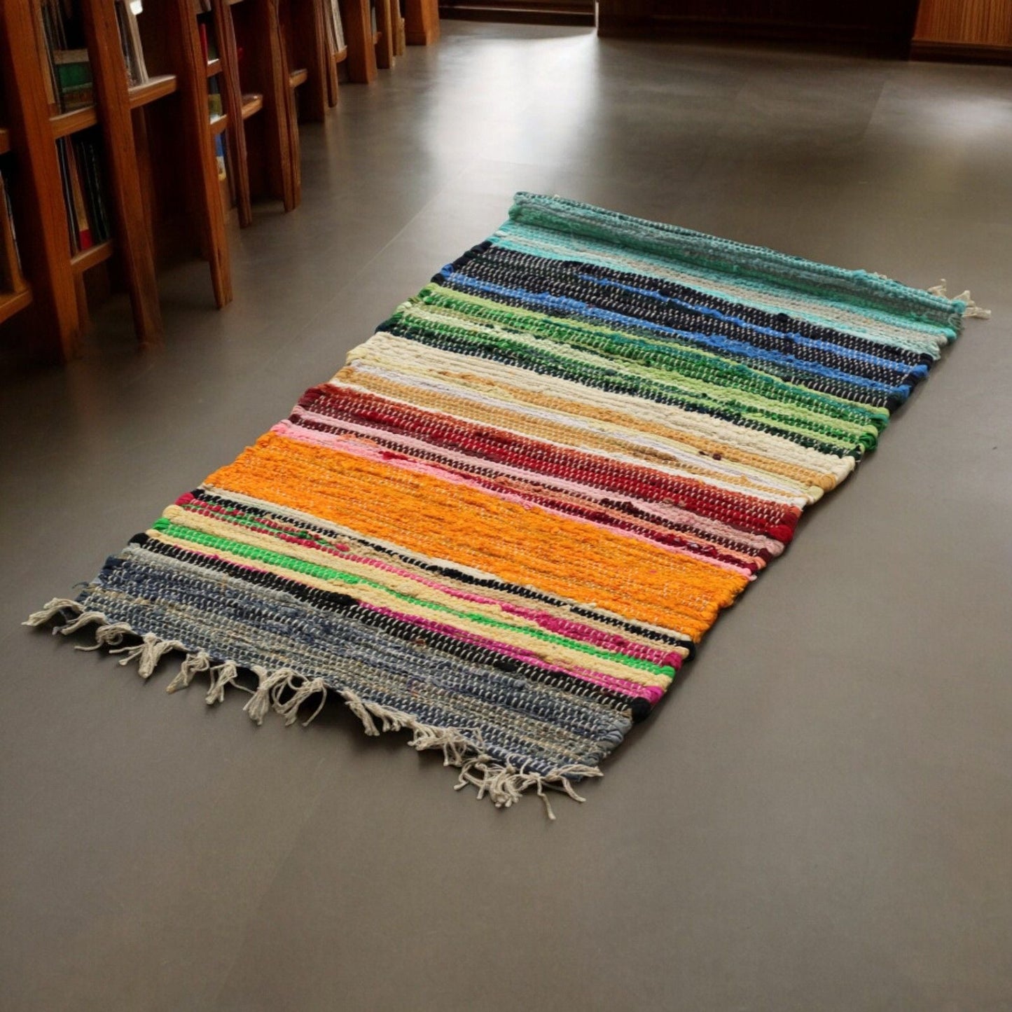 Alt-Tag: Indischer Baumwoll-Läuferteppich aus Stoffresten – Regenbogenfarben 150x90 CM, handgefertigter Baumwoll-Teppich aus Stoffresten mit Regenbogenstreifen und fransigen Enden auf dem Boden