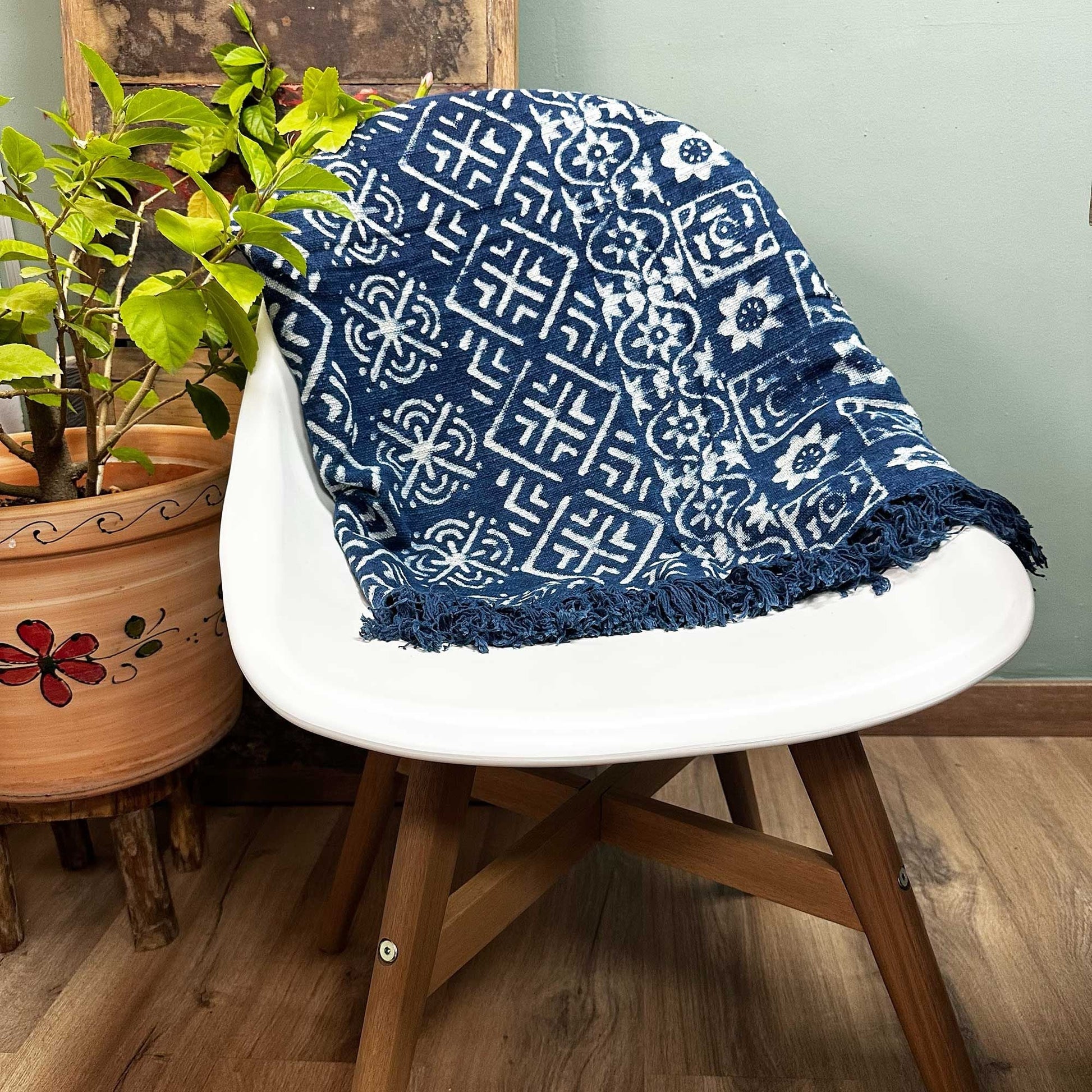 Bomullspläd i indigo – Desi Stripes 170x120 CM, draperad över en vit stol, handgjord bomullsindigopläd med Desi-randmönster och fransar
