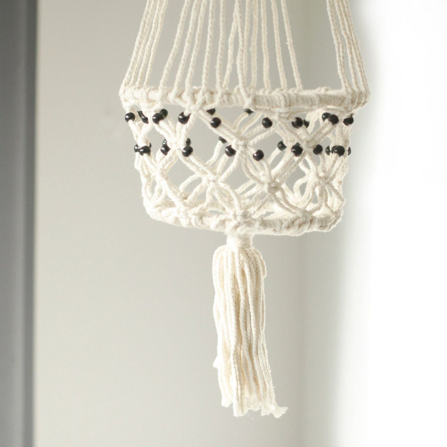 Alt Tag: Cotton Macrame Pot Holder – Large Beaded, white cotton hanging planter holder with black beads and tassel