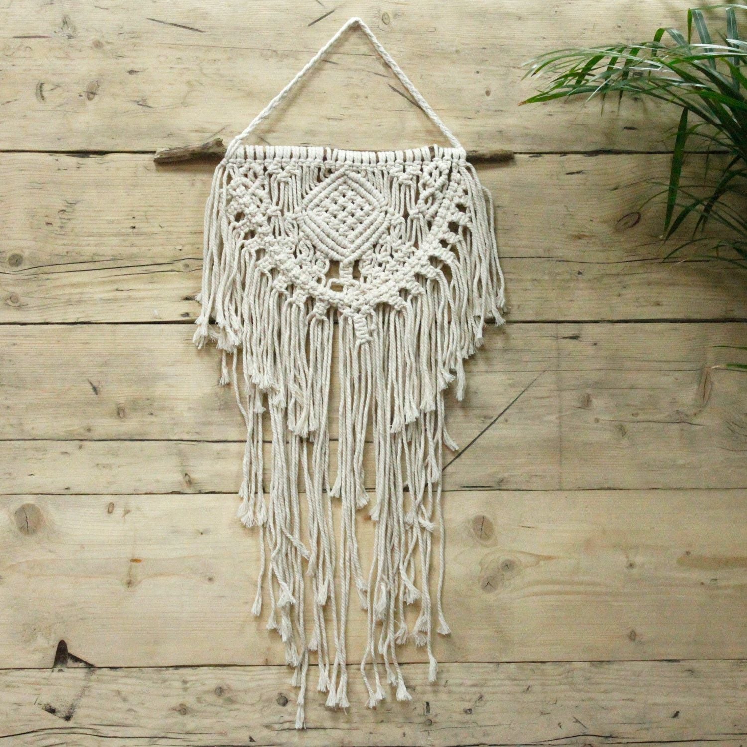 Alt Tag: Cotton Macrame Wall Hanging – 56x40 CM, handwoven cotton wall decor with fringed tassels on wooden rod against rustic wood wall