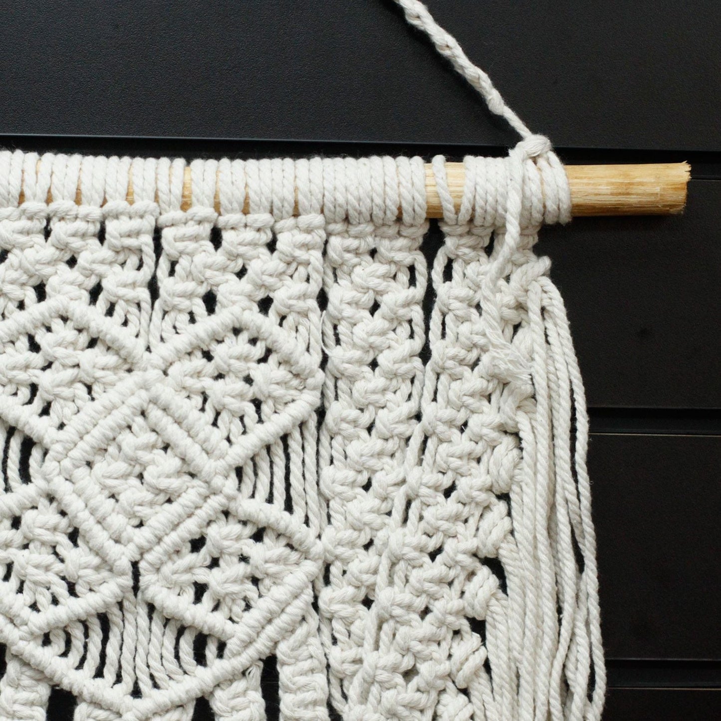 Alt-tagg: Väggbonad i macramé av bomull – 60x40 CM, närbild av vita macraméknutar i bomull på trästav, boho-väggdekor
