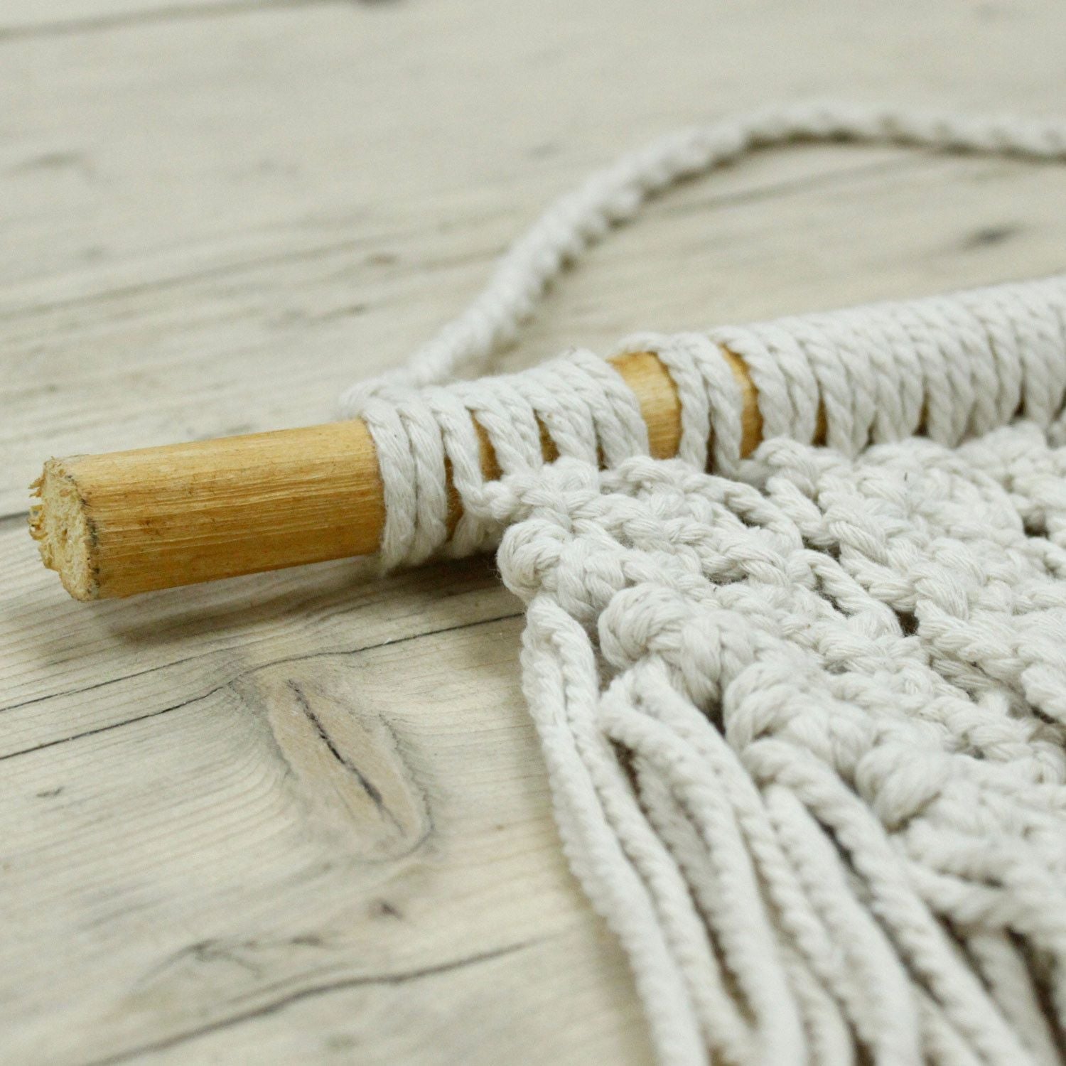 Alt-tagg: Väggbonad i macramé av bomull – 60x40 CM, närbild av vävda bomullsknutar och fransar på rundstav i trä, boho väggdekoration